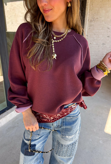 A cozy sweater with a little extra personality! This rich plum sweater features contrasting mauve exposed hems that add a soft, lived-in touch to the classic silhouette. The ribbed hem and sleeves create a comfortable fit while giving the sweater just the right amount of texture. Easy to style and perfect for chilly days, this cozy knit will quickly become a favorite for coffee runs, casual weekends, and fall outings.