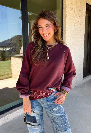 A cozy sweater with a little extra personality! This rich plum sweater features contrasting mauve exposed hems that add a soft, lived-in touch to the classic silhouette. The ribbed hem and sleeves create a comfortable fit while giving the sweater just the right amount of texture. Easy to style and perfect for chilly days, this cozy knit will quickly become a favorite for coffee runs, casual weekends, and fall outings.