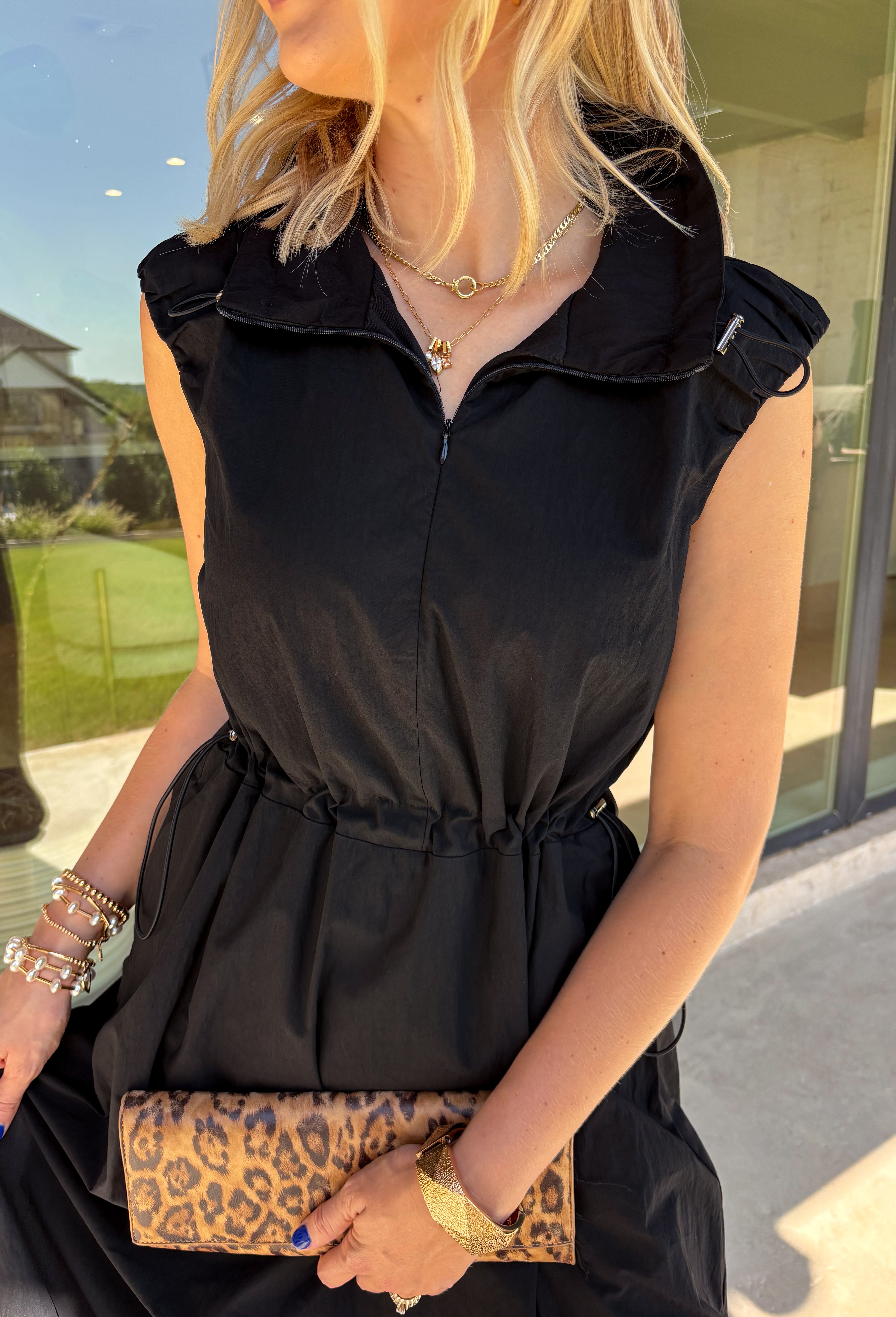 Meet your new throw-on-and-go favorite with this black utility-inspired midi dress from Entro. The classic black color keeps it versatile, while the zipper-front closure and adjustable waist give it a sporty, modern feel. A bubble hem adds shape and a fun unexpected finish, while the sleeveless silhouette makes it easy to wear now and layer as the temperatures cool down. Complete with convenient side pockets, this dress is ready for busy workdays, weekend plans, travel days, and everything in between.