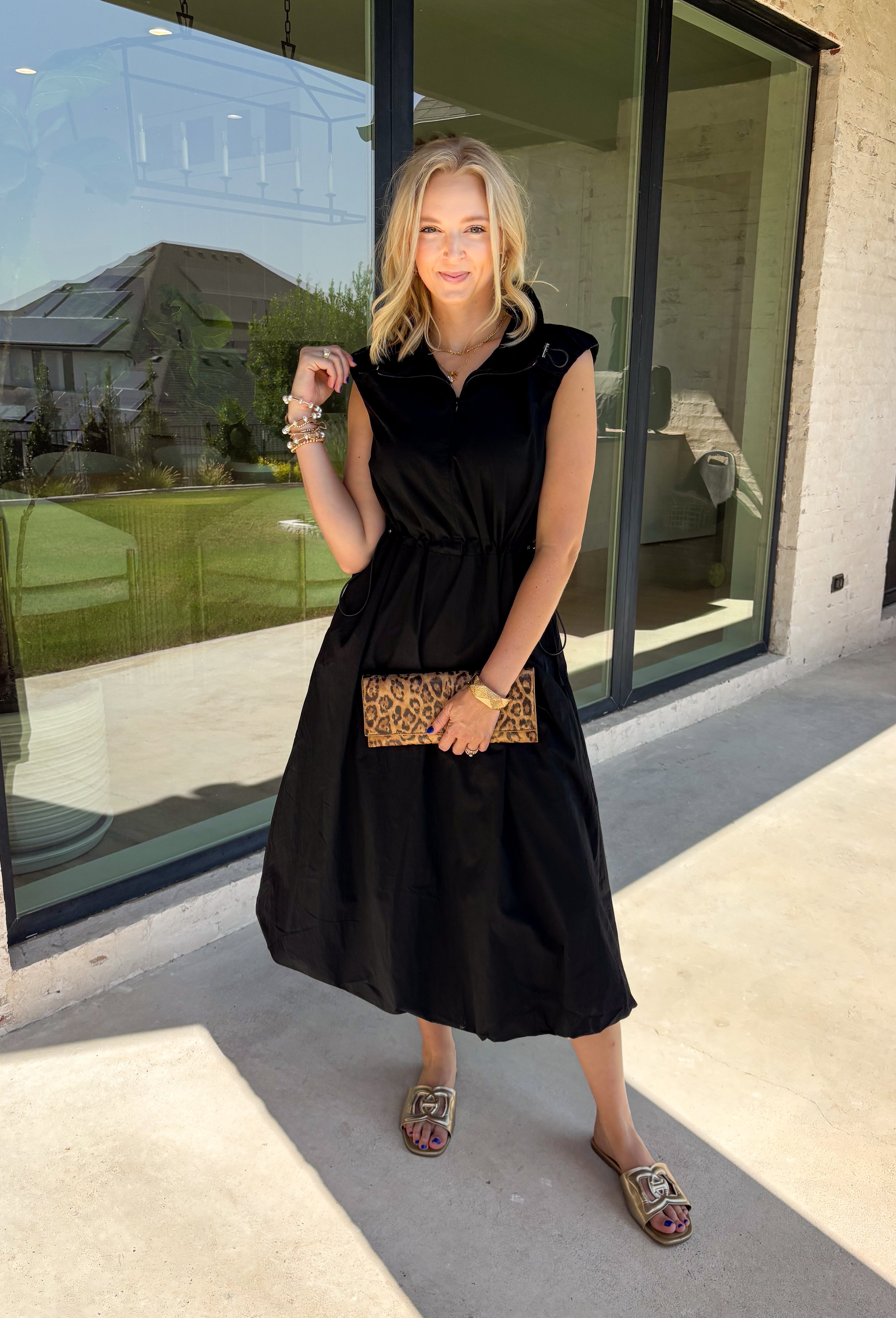 Meet your new throw-on-and-go favorite with this black utility-inspired midi dress from Entro. The classic black color keeps it versatile, while the zipper-front closure and adjustable waist give it a sporty, modern feel. A bubble hem adds shape and a fun unexpected finish, while the sleeveless silhouette makes it easy to wear now and layer as the temperatures cool down. Complete with convenient side pockets, this dress is ready for busy workdays, weekend plans, travel days, and everything in between.