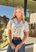 Fresh, feminine, and perfect for spring days, this cream gauze top by Umgee is full of cheerful charm. Featuring a colorful floral print in pink, green, and blue, this lightweight cotton top feels breezy and effortless. The blue scallop lace trim along the front adds a sweet detail, while the ruffled neckline and elastic cuff sleeves give it a soft, romantic finish that’s easy to wear all season long.