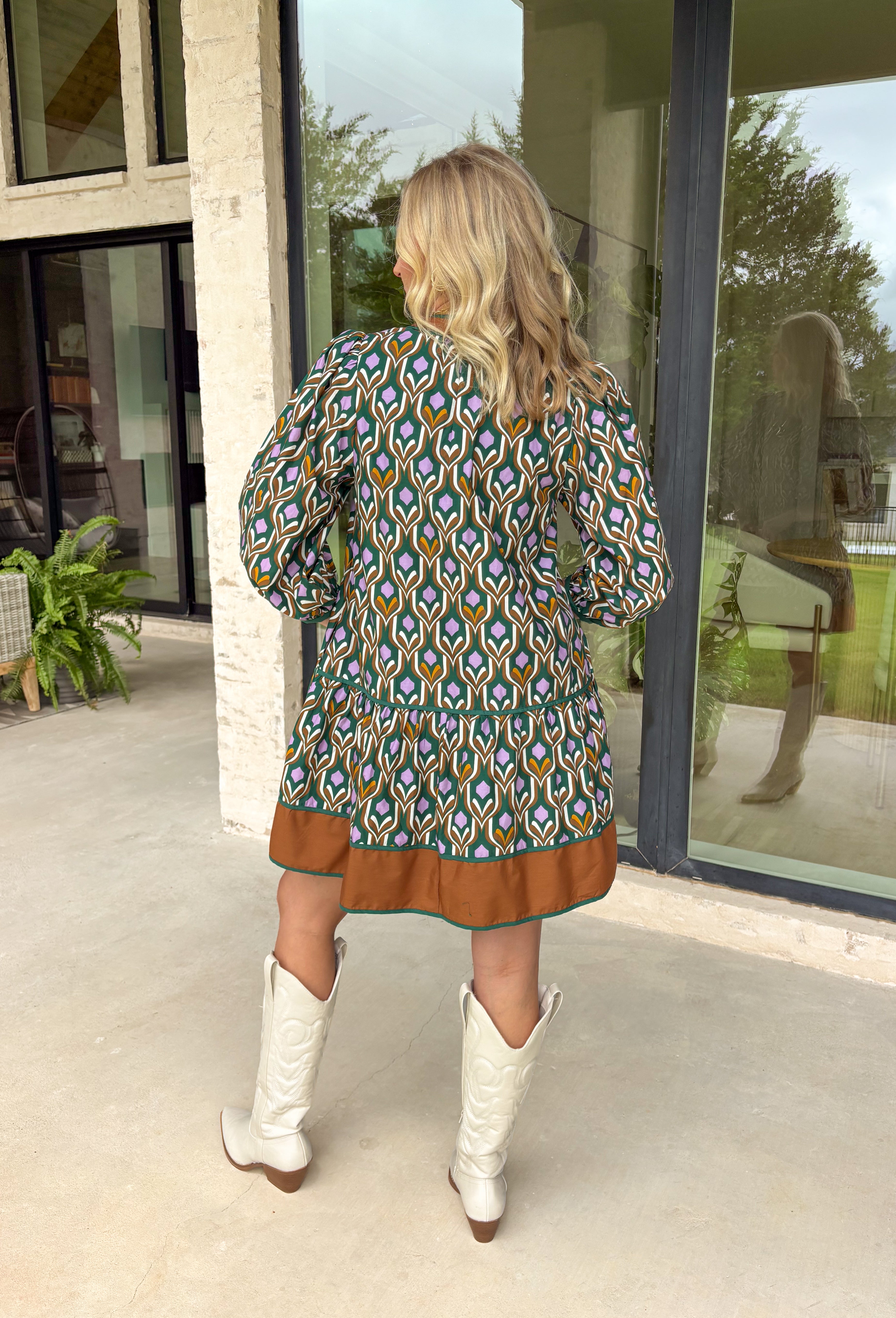 Chic and full of seasonal charm, this hunter green mini dress by Entro brings a fresh take on winter dressing. Featuring a geometric print in tan, white, brown, and lavender, it adds a modern twist to your cold-weather wardrobe. The contrast binding and ruffle hem offer feminine flair, while the lined design and side pocket make it as comfortable as it is stylish.