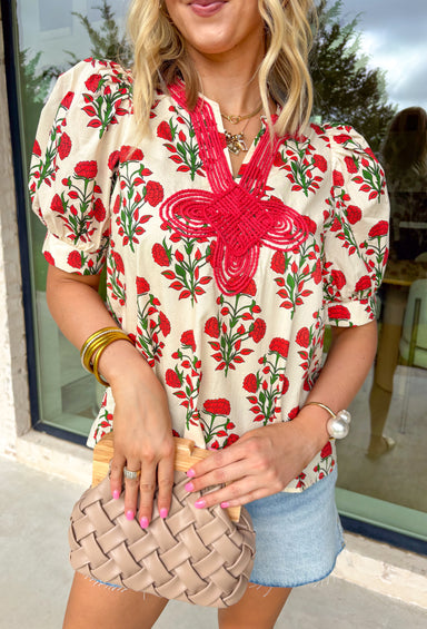 Easygoing with a touch of boho charm, this cream short sleeve top by Entro is perfect for laid-back spring days. Featuring a red floral print with fresh pops of green, it brings just the right amount of color to a neutral base. The macramé-style rope detailing along the top adds beautiful texture and a relaxed, artisan feel that makes this piece stand out while still being easy to wear. Lightweight cotton keeps it comfortable and breathable all season long.