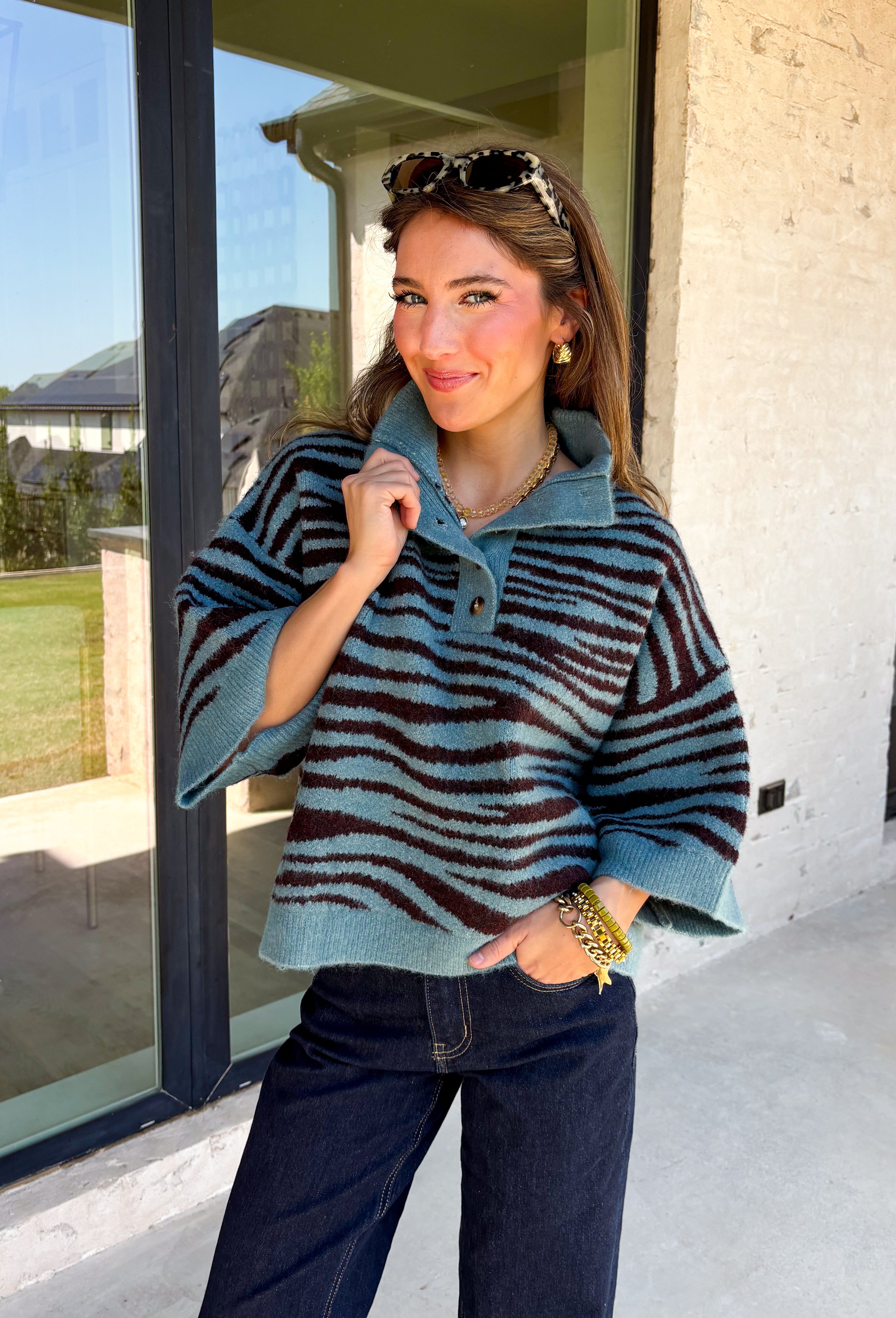 A dusty blue background gives this cozy knit sweater from Entro a fresh pop of color for the season. The darker abstract animal print creates a bold contrast against the dusty blue shade, adding plenty of personality without being difficult to style. A stand neckline and partial button-front closure bring a classic touch to the relaxed knit silhouette, while the ¾ sleeves make it a great option for transitional weather. 
