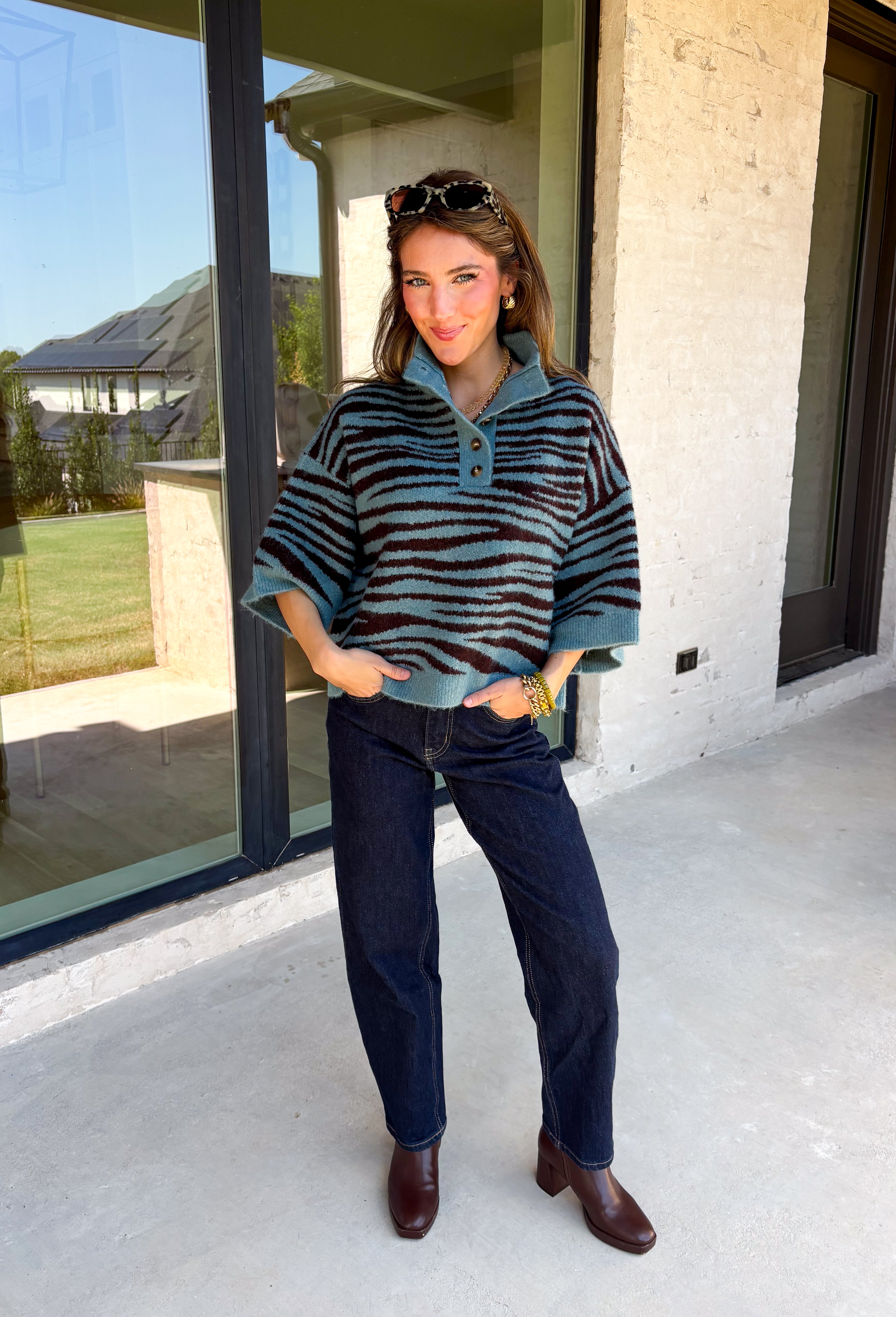 A dusty blue background gives this cozy knit sweater from Entro a fresh pop of color for the season. The darker abstract animal print creates a bold contrast against the dusty blue shade, adding plenty of personality without being difficult to style. A stand neckline and partial button-front closure bring a classic touch to the relaxed knit silhouette, while the ¾ sleeves make it a great option for transitional weather. 