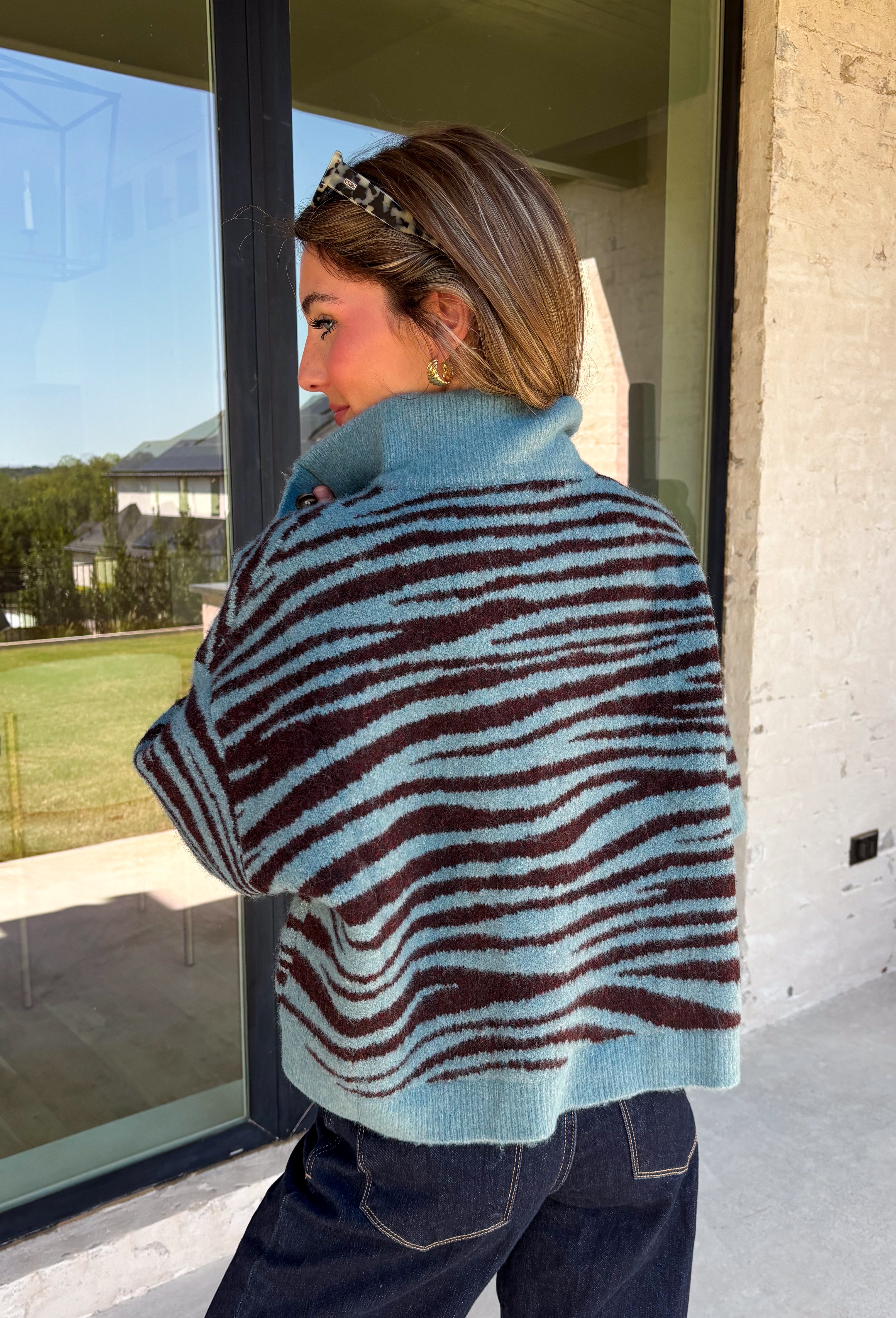 A dusty blue background gives this cozy knit sweater from Entro a fresh pop of color for the season. The darker abstract animal print creates a bold contrast against the dusty blue shade, adding plenty of personality without being difficult to style. A stand neckline and partial button-front closure bring a classic touch to the relaxed knit silhouette, while the ¾ sleeves make it a great option for transitional weather. 