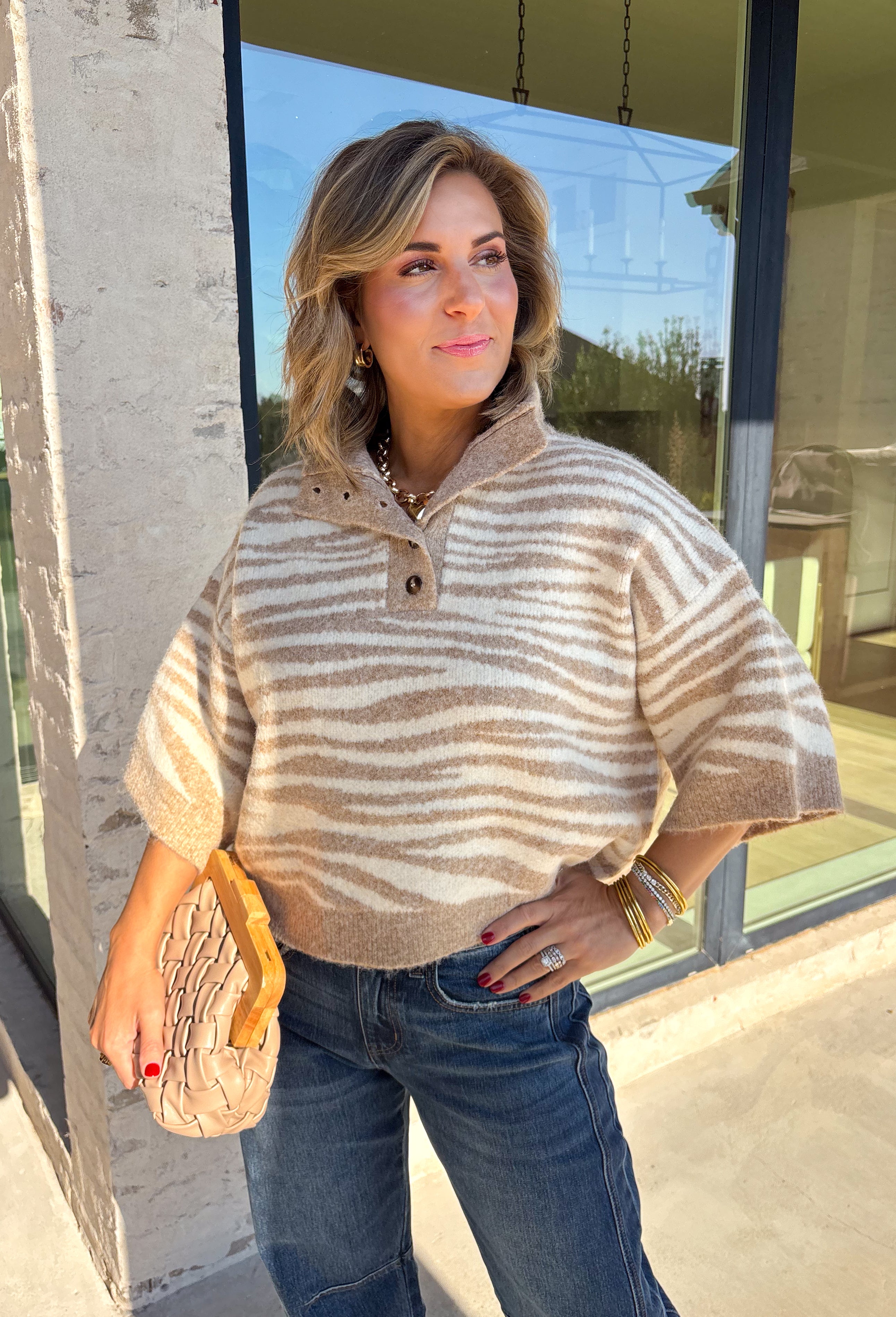 A neutral animal print gives this cozy knit top from Entro plenty of personality while keeping it easy to mix into your fall wardrobe. The abstract pattern brings together versatile neutral shades for a fresh take on a classic animal print. A stand neckline and partial button-front closure add structure to the relaxed knit silhouette, while the ¾ sleeves make it a great choice for those in-between weather days. 
