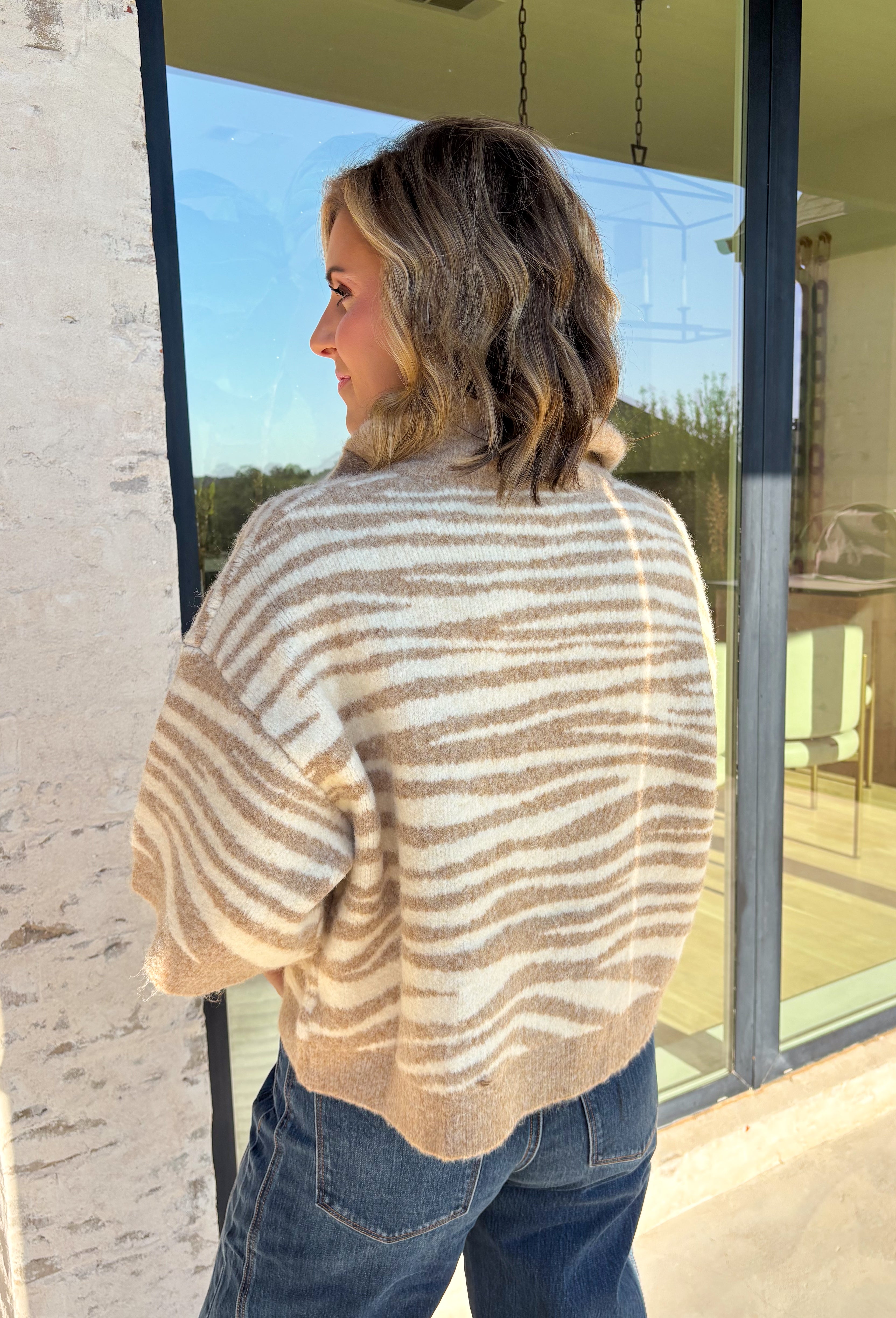 A neutral animal print gives this cozy knit top from Entro plenty of personality while keeping it easy to mix into your fall wardrobe. The abstract pattern brings together versatile neutral shades for a fresh take on a classic animal print. A stand neckline and partial button-front closure add structure to the relaxed knit silhouette, while the ¾ sleeves make it a great choice for those in-between weather days. 