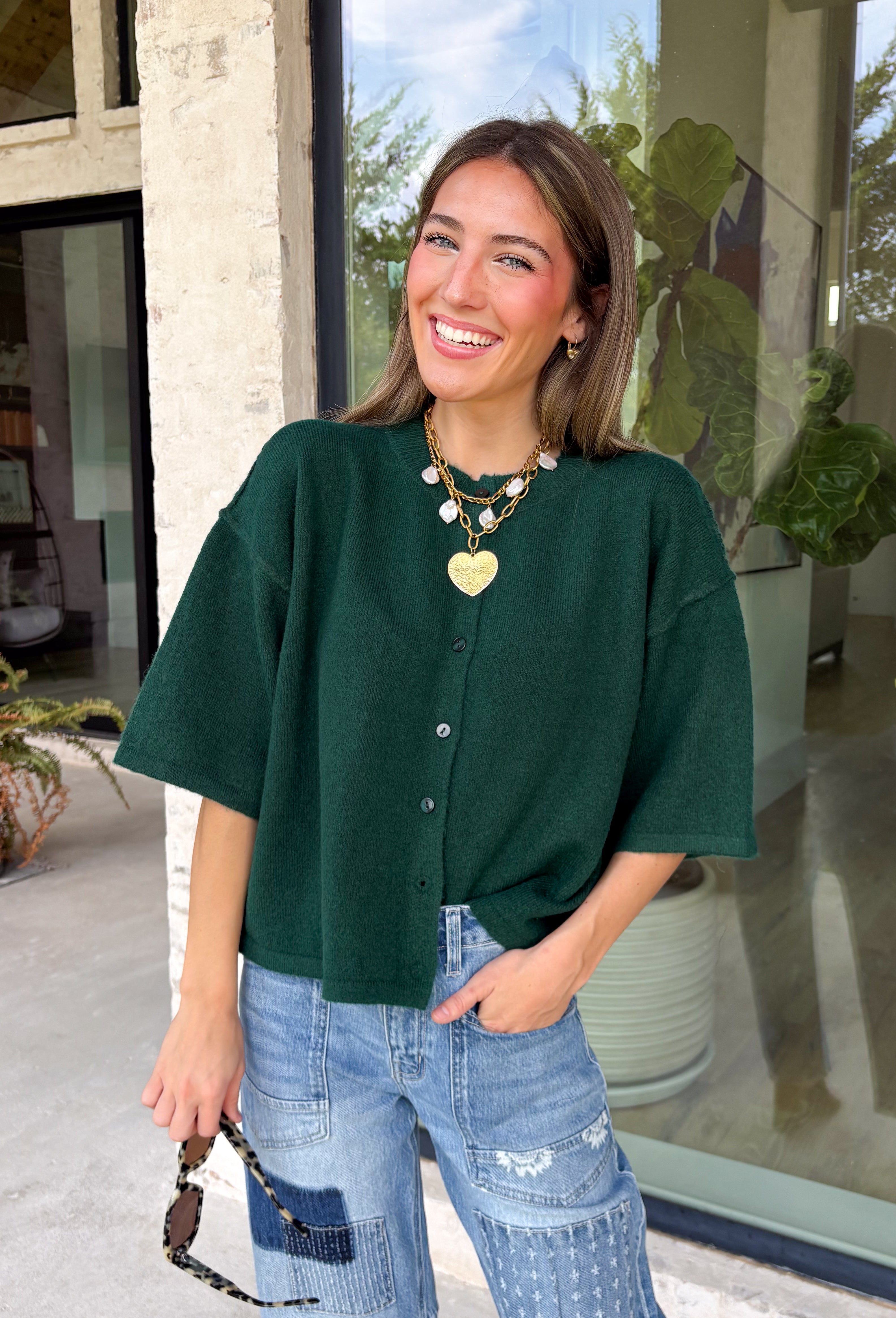 Cozy, classic, and endlessly versatile, this button-down cardigan from Double Zero is the perfect layering piece for the season. Designed in a rich dark green hue, this soft knit cardigan is easy to style with everything from denim to dresses. The ribbed neckline adds a timeless touch, while the cozy knit construction keeps you comfortable throughout the day. Wear it buttoned as a sweater or open over your favorite basics for an effortlessly polished fall look.