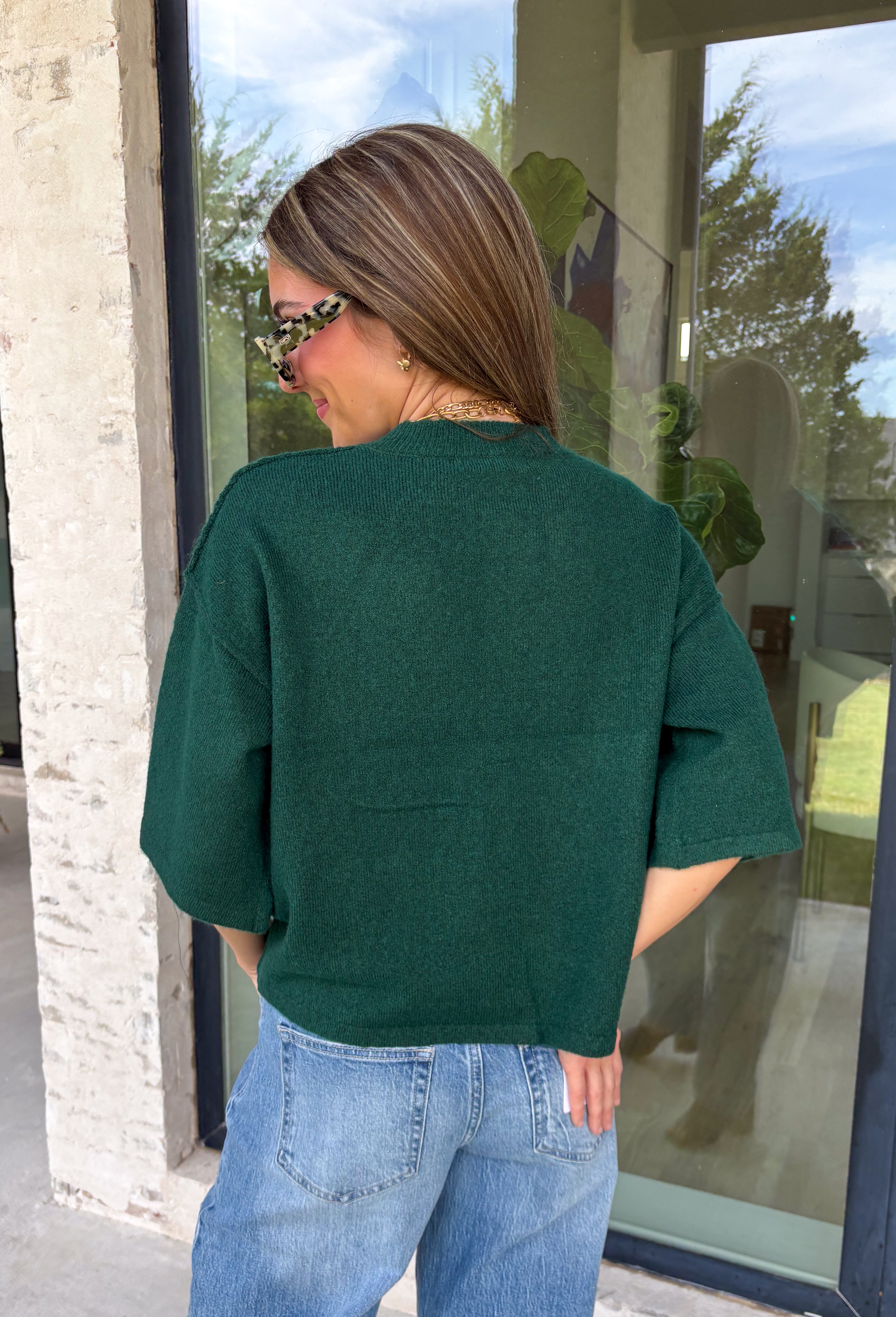 Cozy, classic, and endlessly versatile, this button-down cardigan from Double Zero is the perfect layering piece for the season. Designed in a rich dark green hue, this soft knit cardigan is easy to style with everything from denim to dresses. The ribbed neckline adds a timeless touch, while the cozy knit construction keeps you comfortable throughout the day. Wear it buttoned as a sweater or open over your favorite basics for an effortlessly polished fall look.