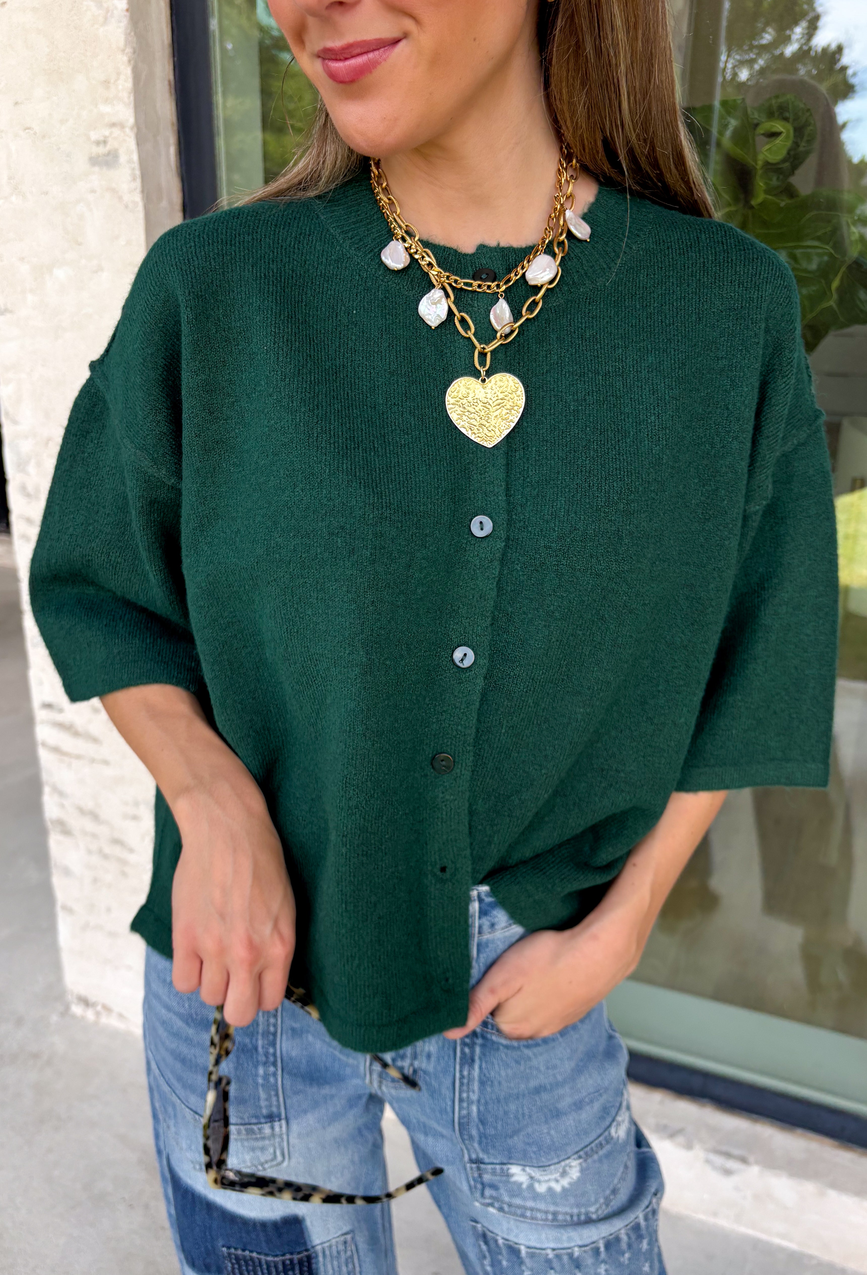 Cozy, classic, and endlessly versatile, this button-down cardigan from Double Zero is the perfect layering piece for the season. Designed in a rich dark green hue, this soft knit cardigan is easy to style with everything from denim to dresses. The ribbed neckline adds a timeless touch, while the cozy knit construction keeps you comfortable throughout the day. Wear it buttoned as a sweater or open over your favorite basics for an effortlessly polished fall look.