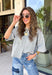 Cozy, classic, and endlessly versatile, this button-down cardigan from Double Zero is the perfect layering piece for the season. Designed in a heather grey hue, this soft knit cardigan is easy to style with everything from denim to dresses. The ribbed neckline adds a timeless touch, while the cozy knit construction keeps you comfortable throughout the day. Wear it buttoned as a sweater or open over your favorite basics for an effortlessly polished fall look.
