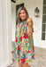 Bright, cheerful, and full of spring charm, this off-white short sleeve dress by Entro is an instant mood booster. Featuring a colorful floral print with pops of green, blue, red, and pink, it feels lively yet easy to wear. The ruffle neckline, ruffle sleeves, and ruffle trim down the front add a soft, feminine touch, while the pleating detail and front button accents give it a polished finish. 