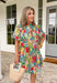 Bright, cheerful, and full of spring charm, this off-white short sleeve dress by Entro is an instant mood booster. Featuring a colorful floral print with pops of green, blue, red, and pink, it feels lively yet easy to wear. The ruffle neckline, ruffle sleeves, and ruffle trim down the front add a soft, feminine touch, while the pleating detail and front button accents give it a polished finish. 