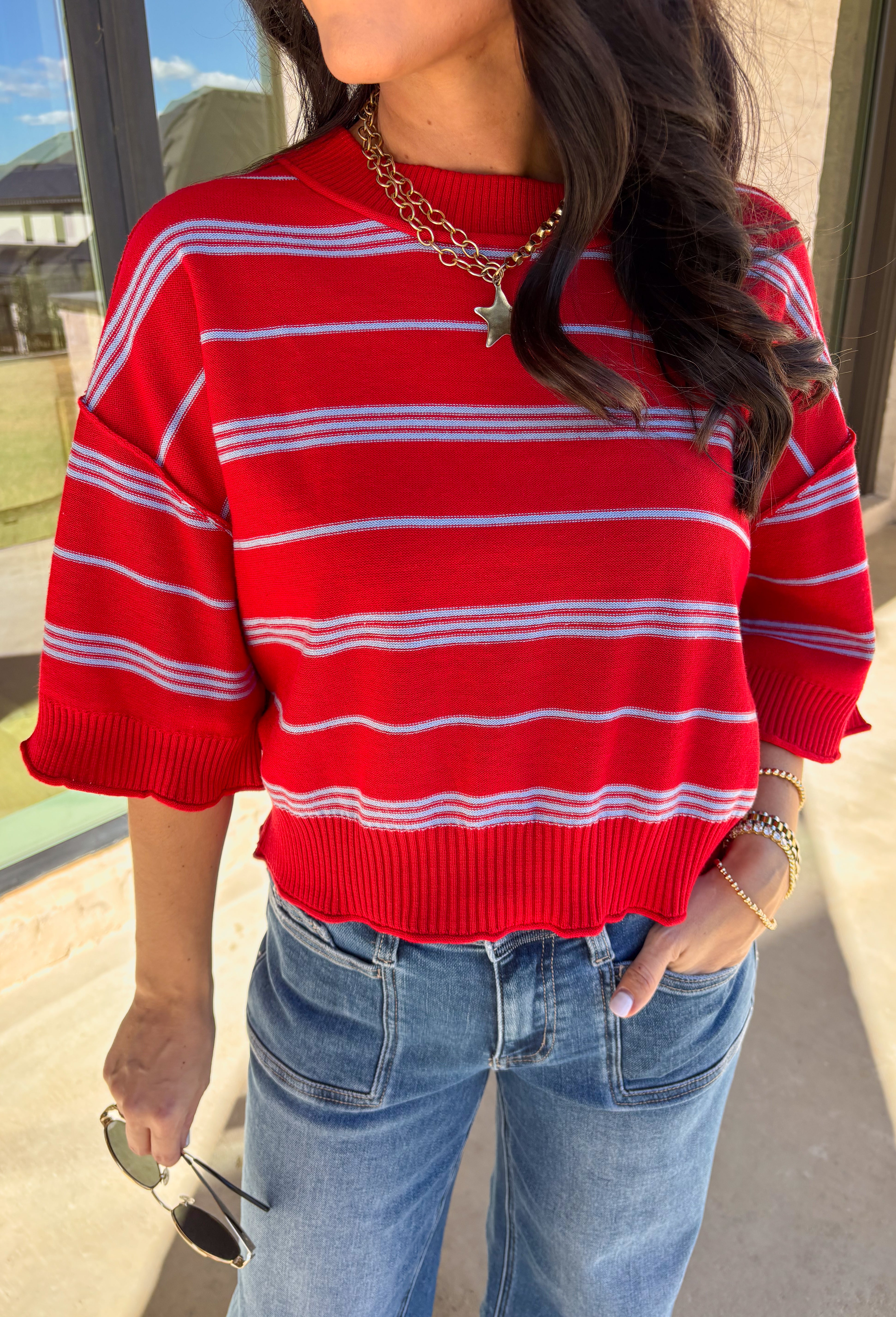 Bold, breezy, and perfect for spring layering, this striped knit top by Entro brings an easy pop of color to your everyday look. Featuring red and light blue stripes with a relaxed drop shoulder fit, it feels laid-back yet polished. The ribbed neckline, cuffs, and hem add subtle structure, while the cropped length keeps it fun and on-trend. Lightweight and comfortable, it’s an easy piece to style all season long.