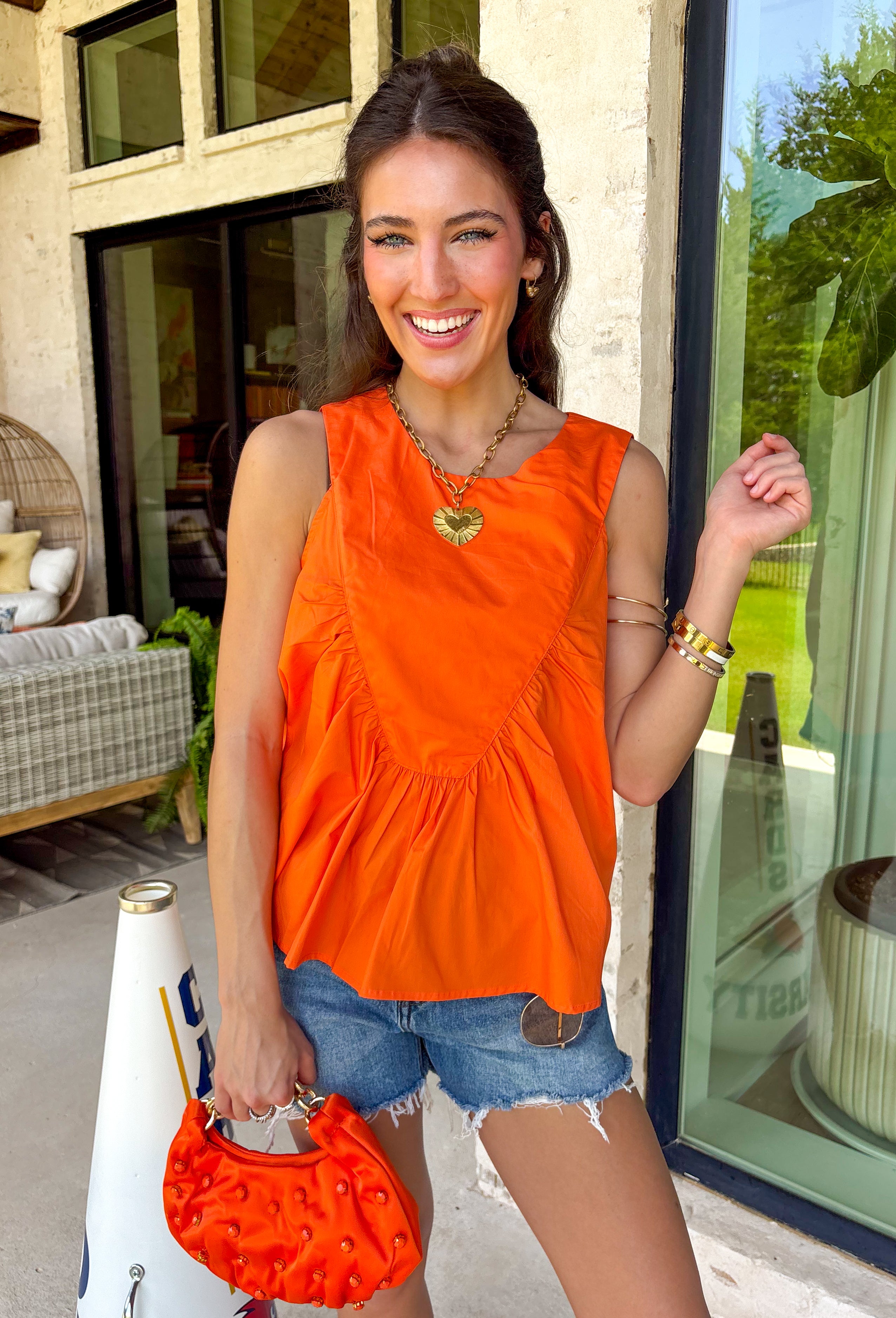 This orange sleeveless top is the versatile staple your wardrobe needs all year long! The vibrant color makes it a standout choice for game day season, while the clean, classic silhouette ensures you'll wear it far beyond football weekends. Designed with a high round neckline and a simple keyhole button closure in the back, it has an elevated look that's easy to dress up or down.