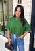 Add a playful pop of color to your fall wardrobe with this cozy short sleeve sweater! Featuring a rich pine green knit with soft pink contrast trim, this sweater is the perfect mix of timeless and fun. The ribbed detailing along the neckline, sleeves, and hem adds a classic finishing touch, while the lightweight knit keeps it comfortable for layering throughout the season. 