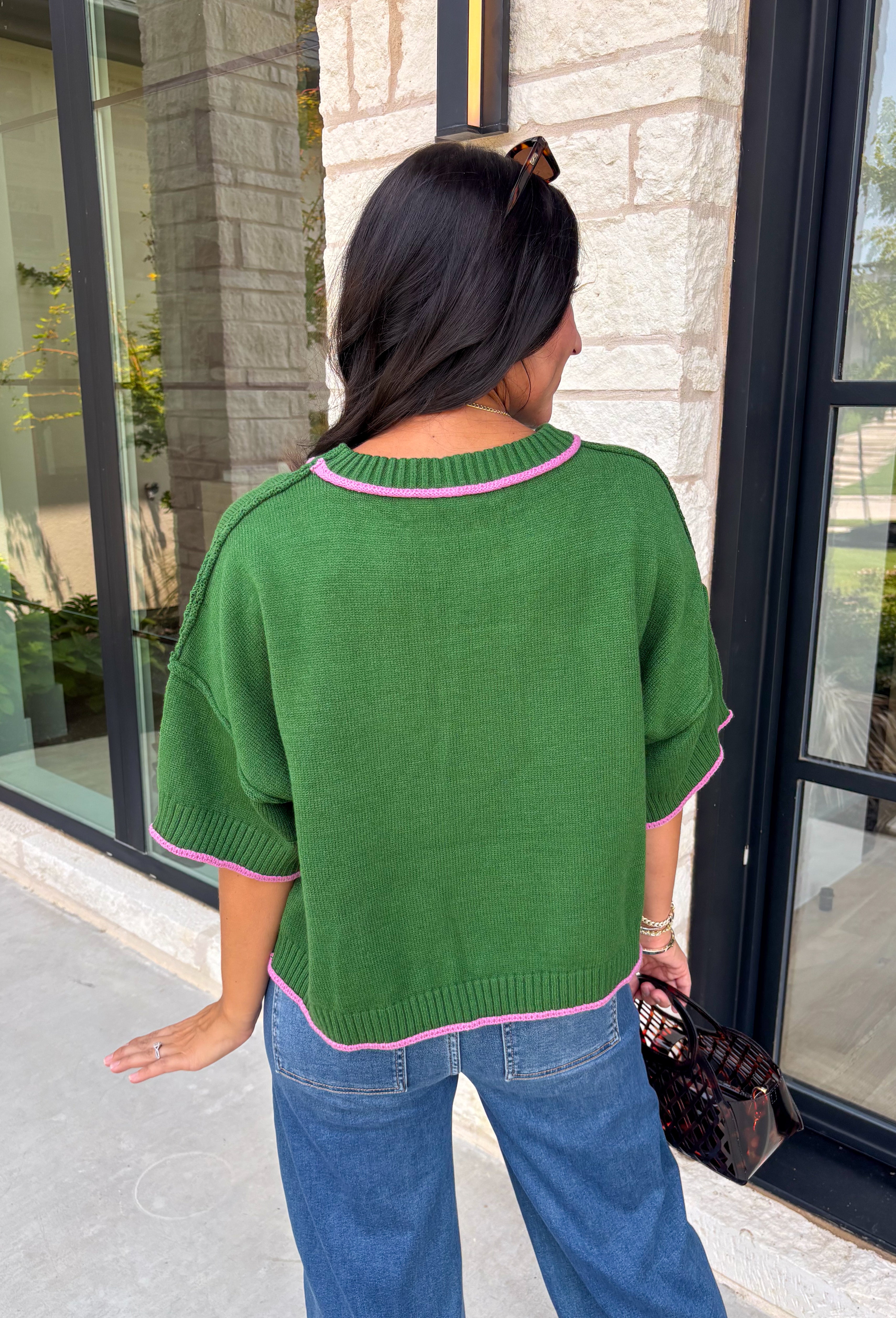 Add a playful pop of color to your fall wardrobe with this cozy short sleeve sweater! Featuring a rich pine green knit with soft pink contrast trim, this sweater is the perfect mix of timeless and fun. The ribbed detailing along the neckline, sleeves, and hem adds a classic finishing touch, while the lightweight knit keeps it comfortable for layering throughout the season. 