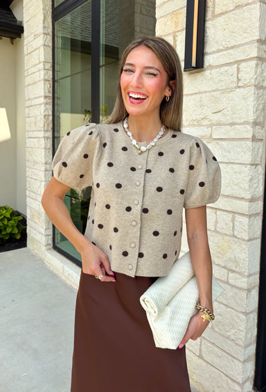 A classic print meets an effortlessly feminine silhouette in this charming knit cardigan! Featuring a soft tan knit with a playful brown polka dot print, this button-down cardigan is finished with sweet puff sleeves for an elevated touch. Whether worn buttoned as a top or layered over your favorite basics, this versatile piece is perfect for everything from office days to coffee dates and weekend outings.