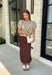 Bring a touch of romance to your fall wardrobe with this stunning chocolate brown satin midi skirt. Crafted from silky satin that catches the light beautifully, this chic skirt is finished with a delicate lace hem for an effortlessly feminine look. The elastic waistband offers all-day comfort while the side zipper creates a flattering, polished fit. Whether you're styling it for holiday gatherings, date nights, or elevating your everyday look, this timeless piece is one you'll love season after season.