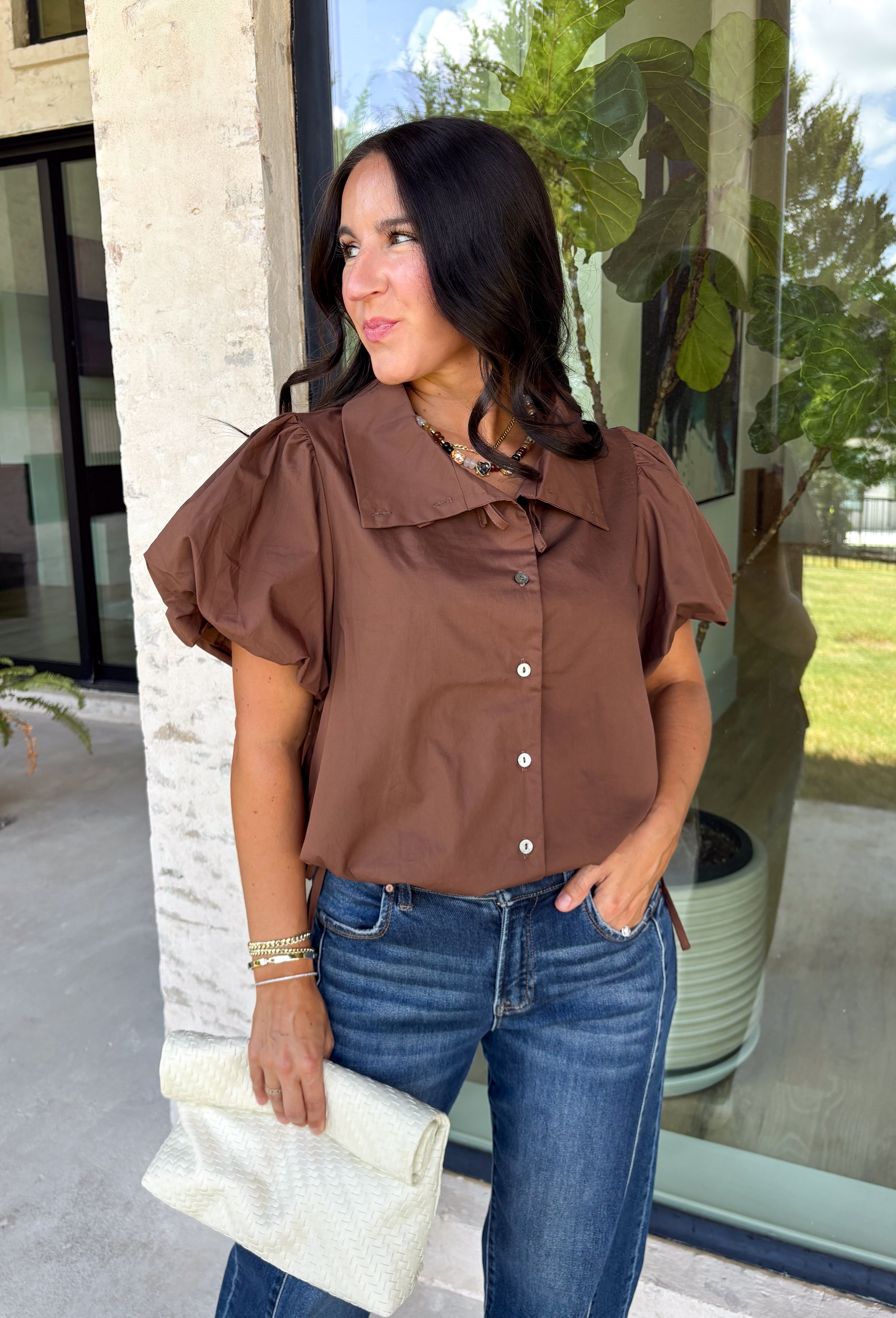 Elevate your everyday wardrobe with this effortlessly polished blouse from Entro. Designed in a rich chocolate brown hue, this timeless top features a classic button-front design with a collared neckline for a sophisticated look. Feminine puff sleeves and charming side tie details add a modern twist, creating a flattering silhouette that's easy to dress up or down. Crafted from breathable cotton, this versatile blouse is perfect for everything from office days to weekend brunches.