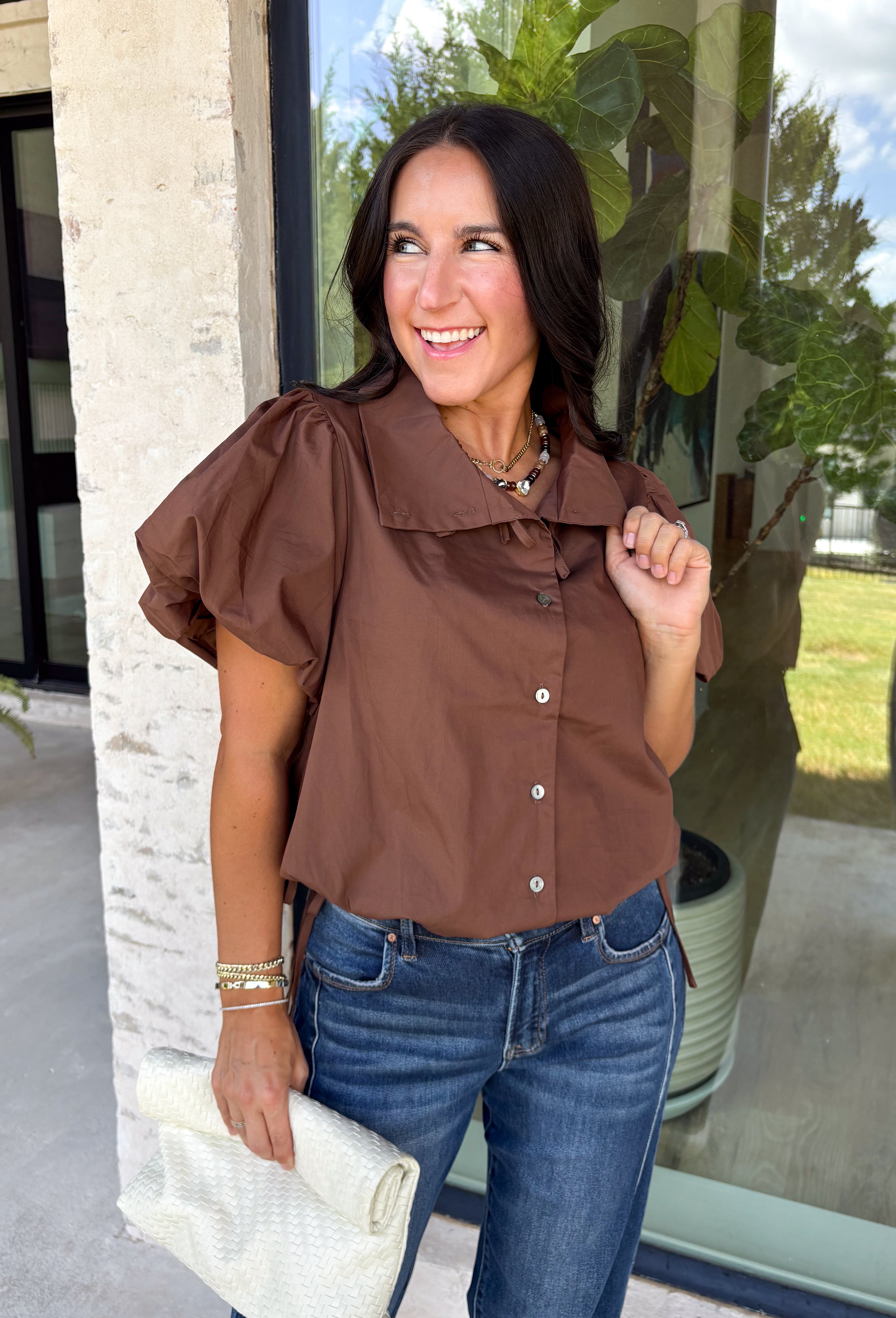 Elevate your everyday wardrobe with this effortlessly polished blouse from Entro. Designed in a rich chocolate brown hue, this timeless top features a classic button-front design with a collared neckline for a sophisticated look. Feminine puff sleeves and charming side tie details add a modern twist, creating a flattering silhouette that's easy to dress up or down. Crafted from breathable cotton, this versatile blouse is perfect for everything from office days to weekend brunches.