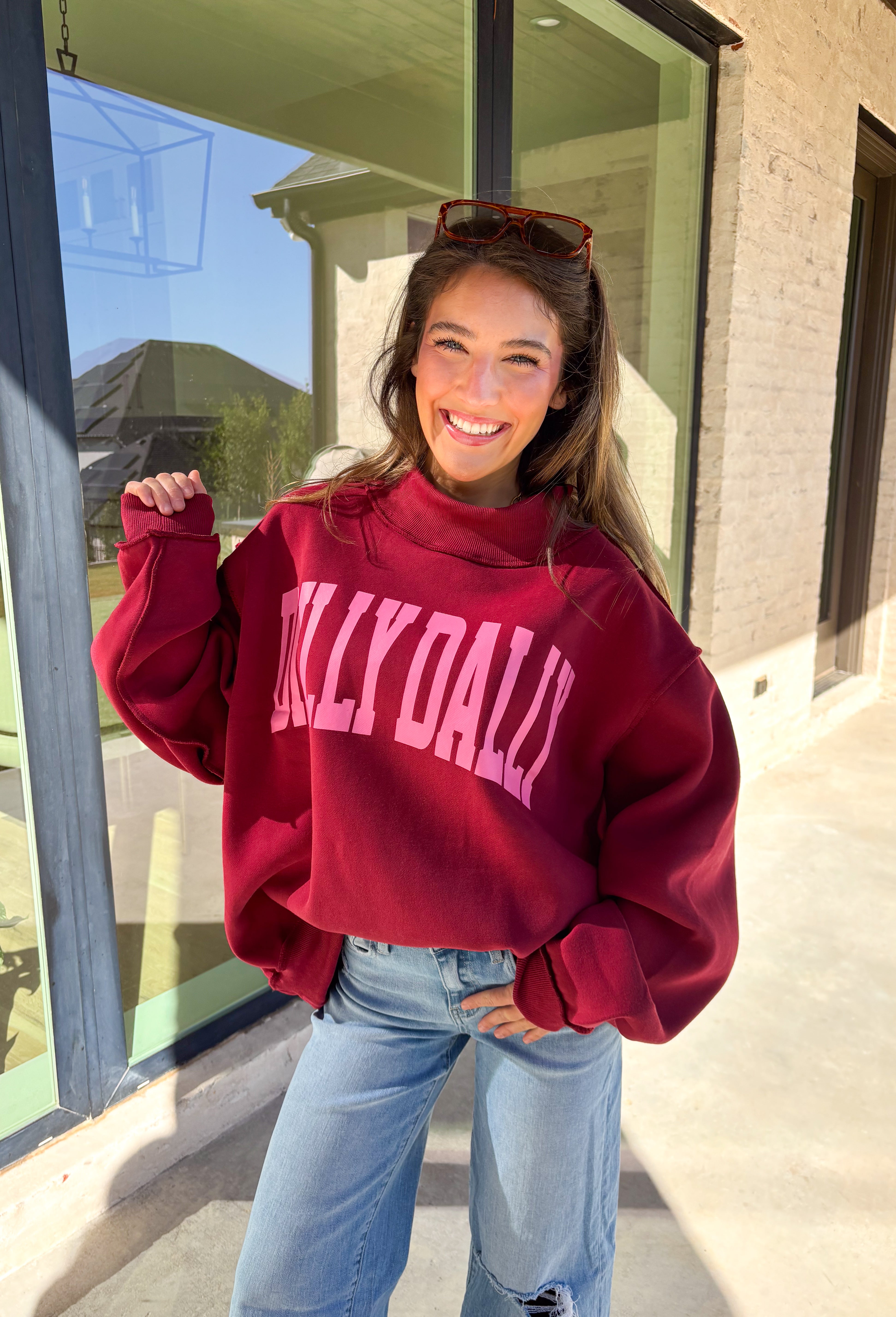 Make your winter wardrobe a little more fun with this playful “Dilly Dally” pullover by Bucket List. Featuring bold hot pink lettering on a rich burgundy backdrop, this cozy mock neck sweatshirt is made for chill days and cheerful moods. With its oversized fit and soft fabric, it’s the perfect mix of comfort and attitude for the season.