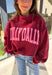 Make your winter wardrobe a little more fun with this playful “Dilly Dally” pullover by Bucket List. Featuring bold hot pink lettering on a rich burgundy backdrop, this cozy mock neck sweatshirt is made for chill days and cheerful moods. With its oversized fit and soft fabric, it’s the perfect mix of comfort and attitude for the season.