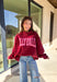 Make your winter wardrobe a little more fun with this playful “Dilly Dally” pullover by Bucket List. Featuring bold hot pink lettering on a rich burgundy backdrop, this cozy mock neck sweatshirt is made for chill days and cheerful moods. With its oversized fit and soft fabric, it’s the perfect mix of comfort and attitude for the season.