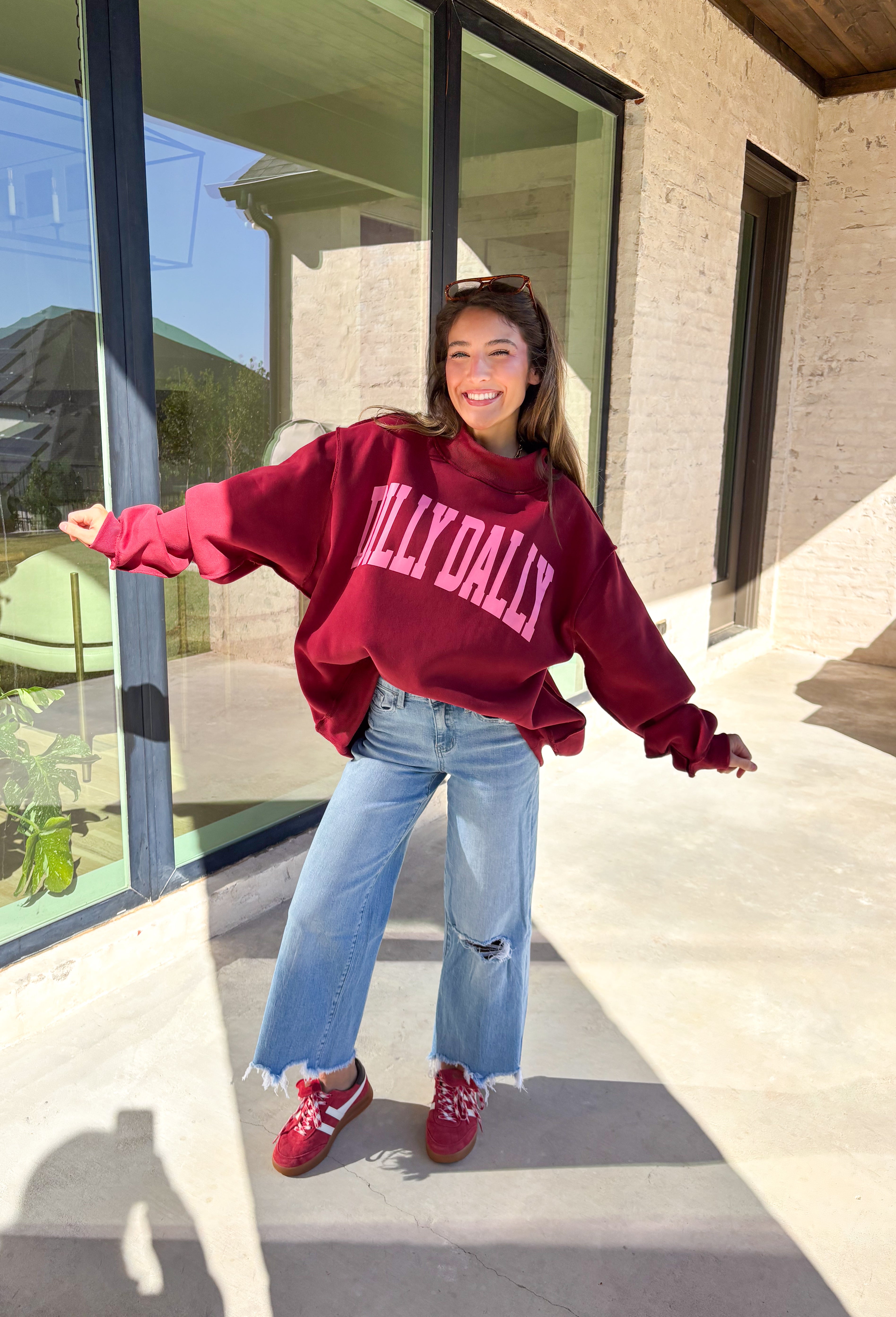 Make your winter wardrobe a little more fun with this playful “Dilly Dally” pullover by Bucket List. Featuring bold hot pink lettering on a rich burgundy backdrop, this cozy mock neck sweatshirt is made for chill days and cheerful moods. With its oversized fit and soft fabric, it’s the perfect mix of comfort and attitude for the season.