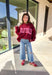 Make your winter wardrobe a little more fun with this playful “Dilly Dally” pullover by Bucket List. Featuring bold hot pink lettering on a rich burgundy backdrop, this cozy mock neck sweatshirt is made for chill days and cheerful moods. With its oversized fit and soft fabric, it’s the perfect mix of comfort and attitude for the season.