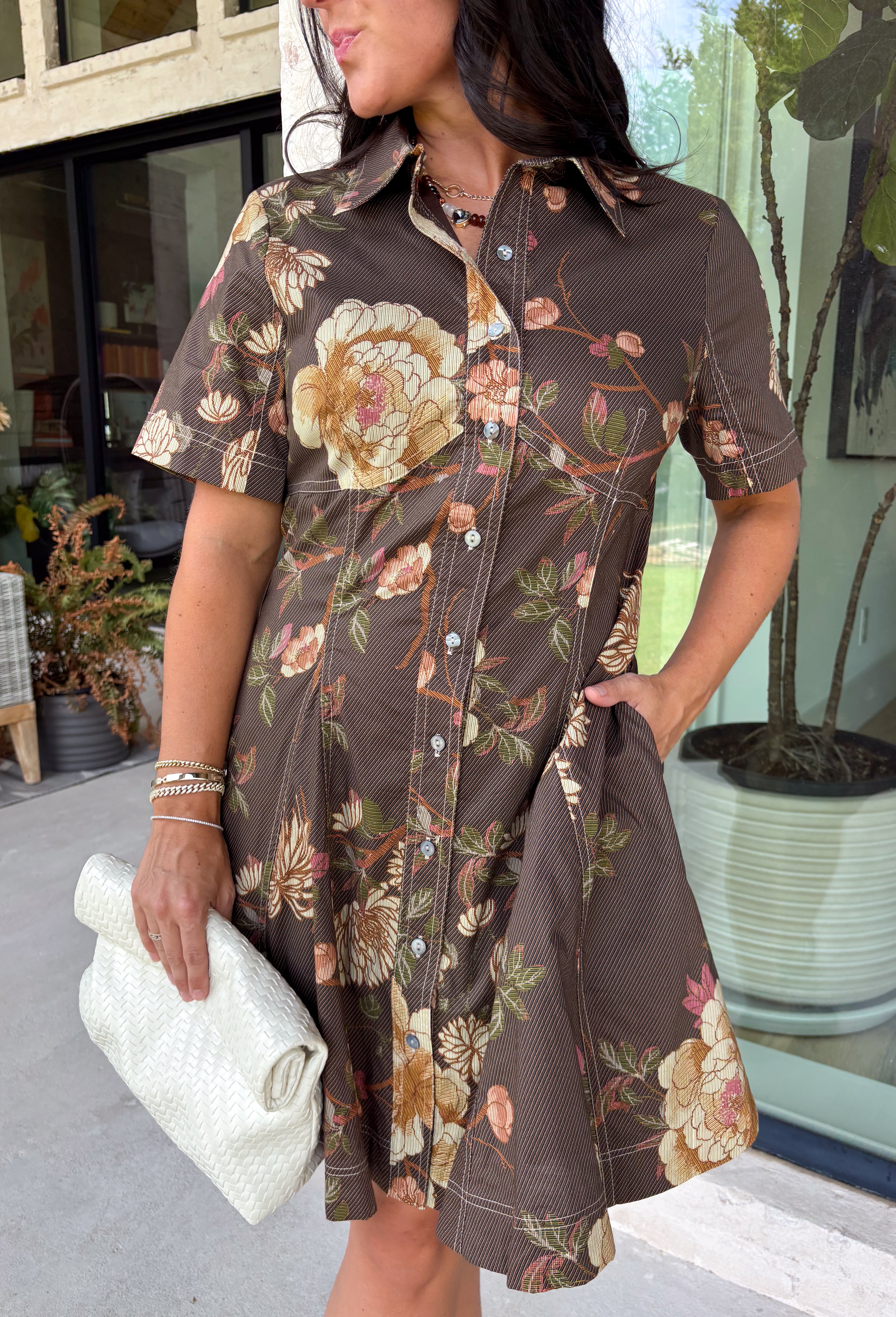 Celebrate the beauty of the season in this effortlessly timeless dress from Entro. Designed in a rich deep olive hue, this button-down dress features a beautiful mix of tan and black stripes paired with a fall-inspired floral print in shades of tan, olive, rust, and brown. The classic button-front silhouette creates an effortlessly polished look, while the fully lined design and convenient side pockets make it as practical as it is beautiful. 