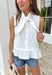 Crisp, classic, and endlessly versatile — this white sleeveless button down top is one you’ll reach for again and again. The clean silhouette keeps it timeless, while the tie detail at the top adds a soft, feminine touch that sets it apart from your basic button downs. Finished with a subtle ruffle hem for a hint of movement and charm, this top is lightweight and breathable in 100% cotton. It’s polished enough for work and easy enough for weekend wear — the kind of staple that works all season long.