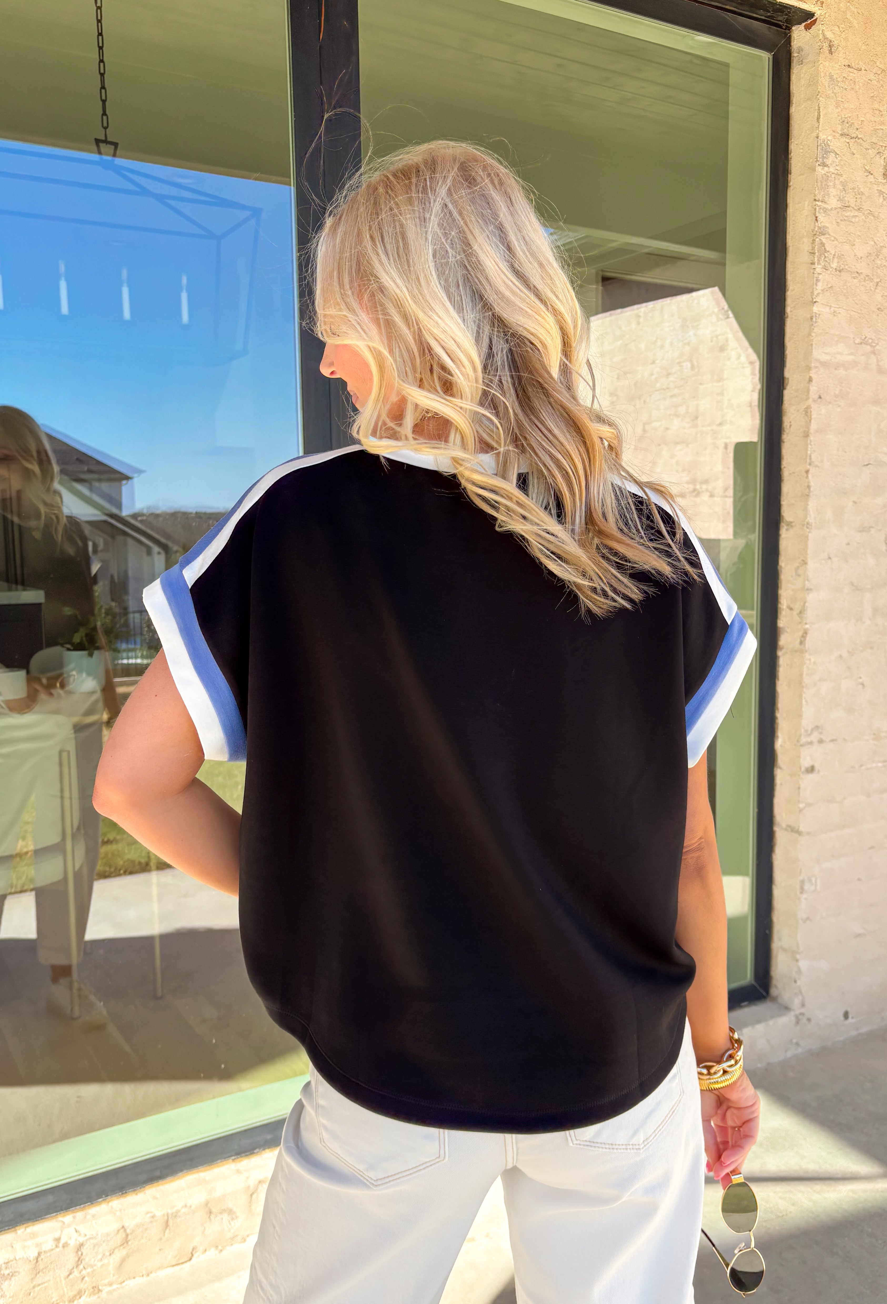 Soft, sporty, and seriously comfortable, this black short sleeve top by Entro is the kind of everyday staple you’ll reach for again and again. Made from a buttery soft fabric, it features crisp white and blue trim along the neckline and sleeves for a fresh pop of contrast. Easy to dress up or down, this top is perfect for spring days when you want to look put together without sacrificing comfort.