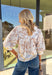 Soft, classic, and perfect for spring, this tan 3/4 sleeve top by Entro is an effortless everyday favorite. Featuring a delicate white floral print throughout, it brings a light, feminine touch to a neutral base. Light peach trim along the hem and sleeve cuffs adds a clean contrast detail, while the collared neckline gives it a polished finish. Made from breathable cotton, this top is easy to wear from workdays to weekend plans.