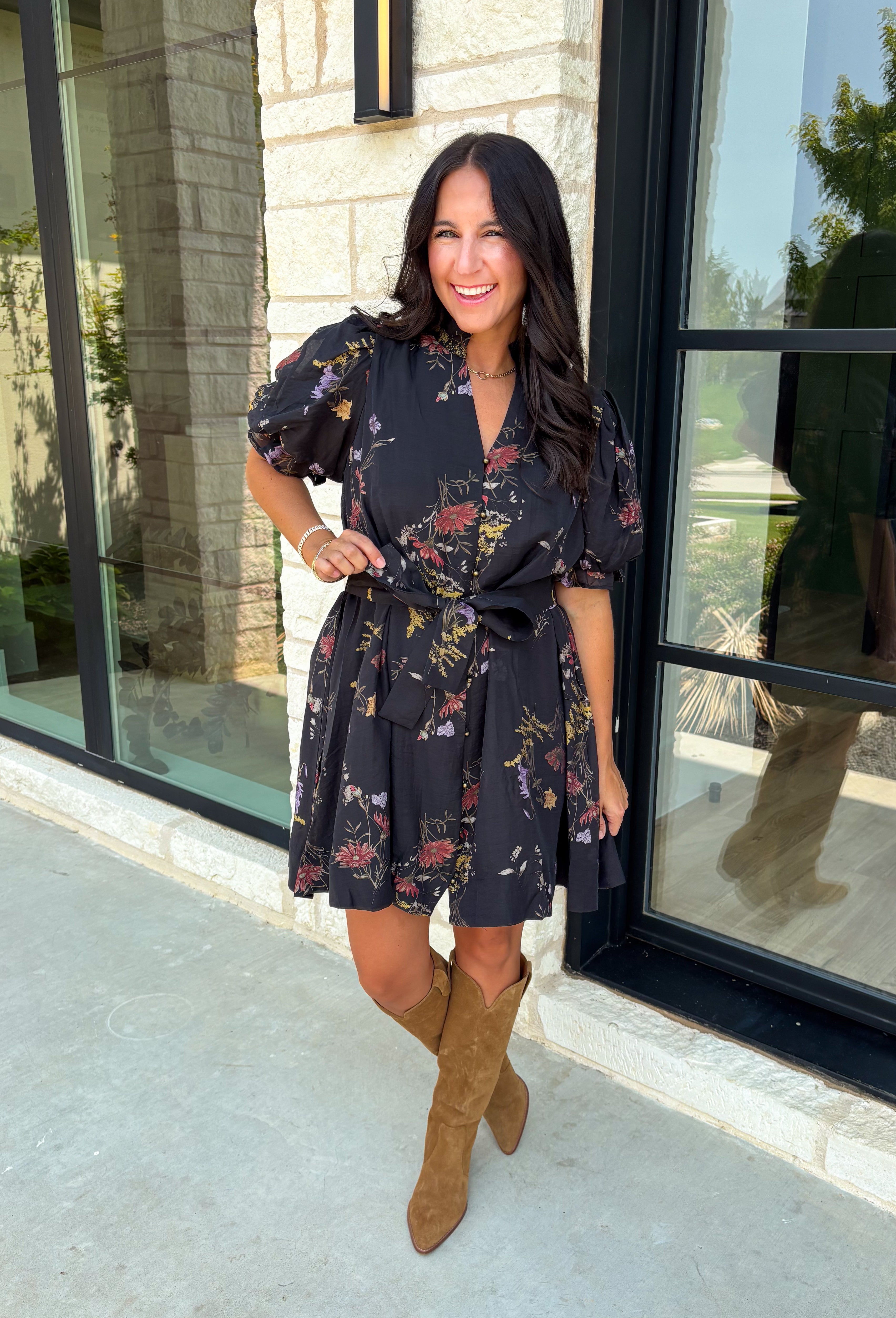 Embrace the beauty of the season in this effortlessly feminine floral dress that's made for all your favorite fall occasions. Designed with a classic black backdrop and adorned with a rich floral print in gorgeous autumn-inspired hues, this dress is the perfect combination of timeless elegance and everyday comfort. The ruffled v-neckline and puff sleeves add a romantic touch, while the self-tie waist creates a flattering silhouette you'll love. 