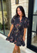 Embrace the beauty of the season in this effortlessly feminine floral dress that's made for all your favorite fall occasions. Designed with a classic black backdrop and adorned with a rich floral print in gorgeous autumn-inspired hues, this dress is the perfect combination of timeless elegance and everyday comfort. The ruffled v-neckline and puff sleeves add a romantic touch, while the self-tie waist creates a flattering silhouette you'll love. 