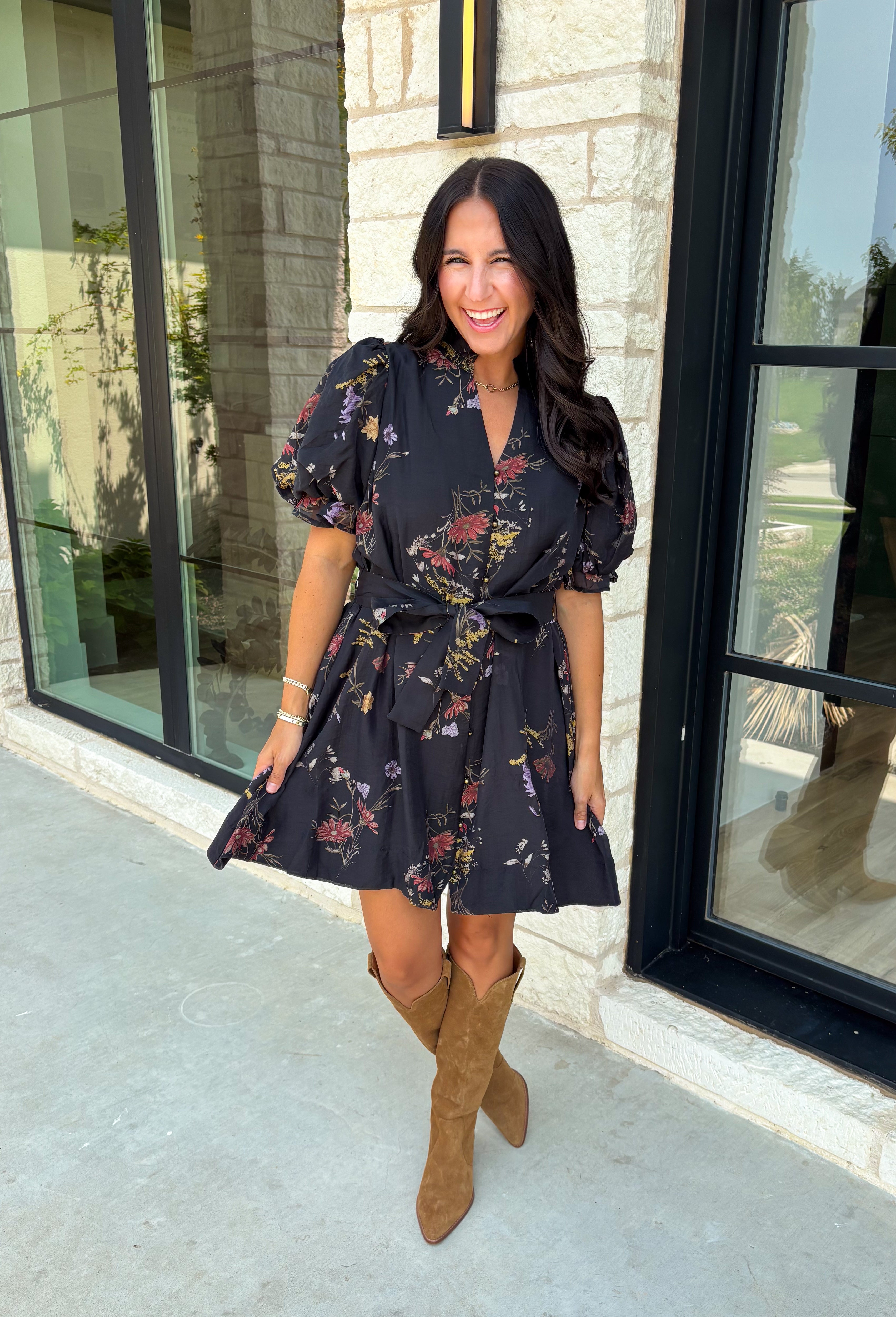 Embrace the beauty of the season in this effortlessly feminine floral dress that's made for all your favorite fall occasions. Designed with a classic black backdrop and adorned with a rich floral print in gorgeous autumn-inspired hues, this dress is the perfect combination of timeless elegance and everyday comfort. The ruffled v-neckline and puff sleeves add a romantic touch, while the self-tie waist creates a flattering silhouette you'll love. 