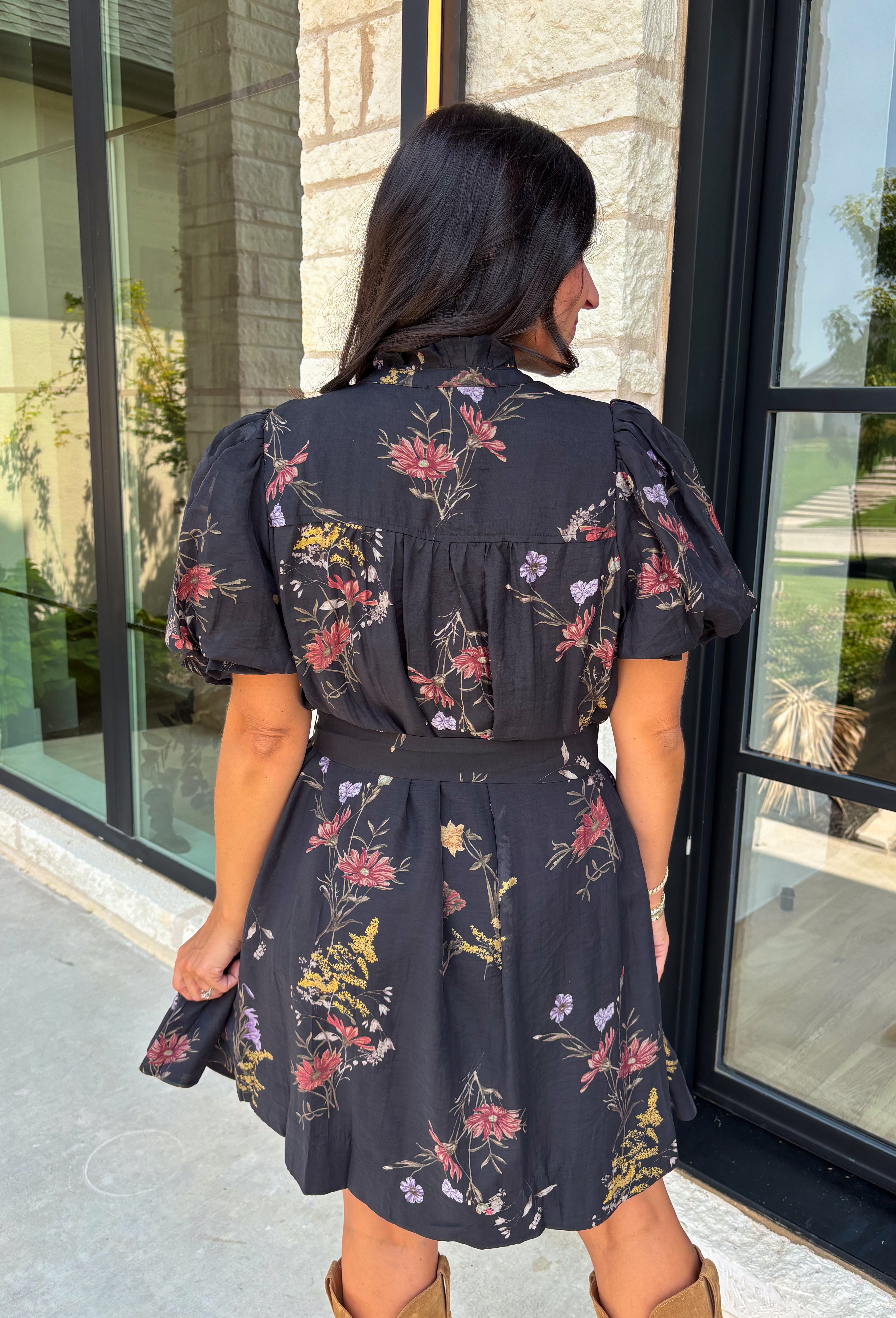 Embrace the beauty of the season in this effortlessly feminine floral dress that's made for all your favorite fall occasions. Designed with a classic black backdrop and adorned with a rich floral print in gorgeous autumn-inspired hues, this dress is the perfect combination of timeless elegance and everyday comfort. The ruffled v-neckline and puff sleeves add a romantic touch, while the self-tie waist creates a flattering silhouette you'll love. 