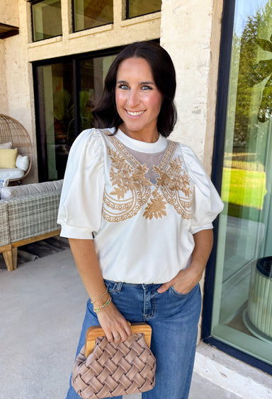 This white short sleeve top is a beautiful blend of soft texture and thoughtful detail, perfect for easy spring styling. The puff sleeves add a touch of volume and femininity, while the tan embroidery along the front creates a warm, eye-catching contrast. Delicate mesh detailing on the front adds dimension and an elevated finish, making this top feel extra special without being fussy. Lightweight and breathable, it’s an effortless piece you can dress up or keep casual all season long.