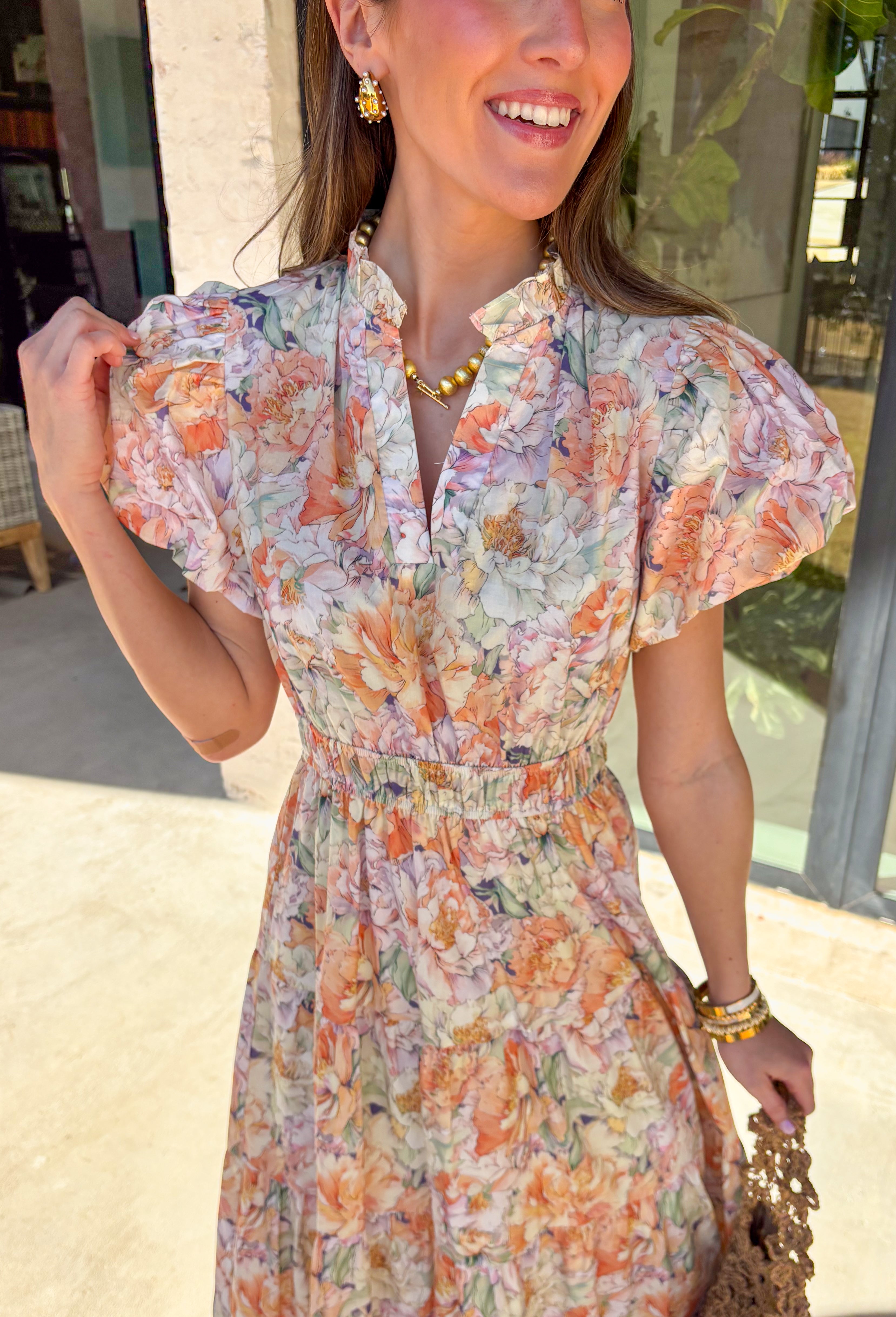 Soft, romantic, and made for spring days, this pastel floral maxi dress by Entro is as easy as it is pretty. Featuring a light, airy floral print in soft spring hues, this dress flows beautifully with its tiered skirt and flattering elastic waist. The subtle ruffle neckline and v-neckline add a delicate touch, while the puff sleeves bring just the right amount of charm. Fully lined and crafted from breathable cotton, it’s perfect for everything from brunch to spring celebrations.