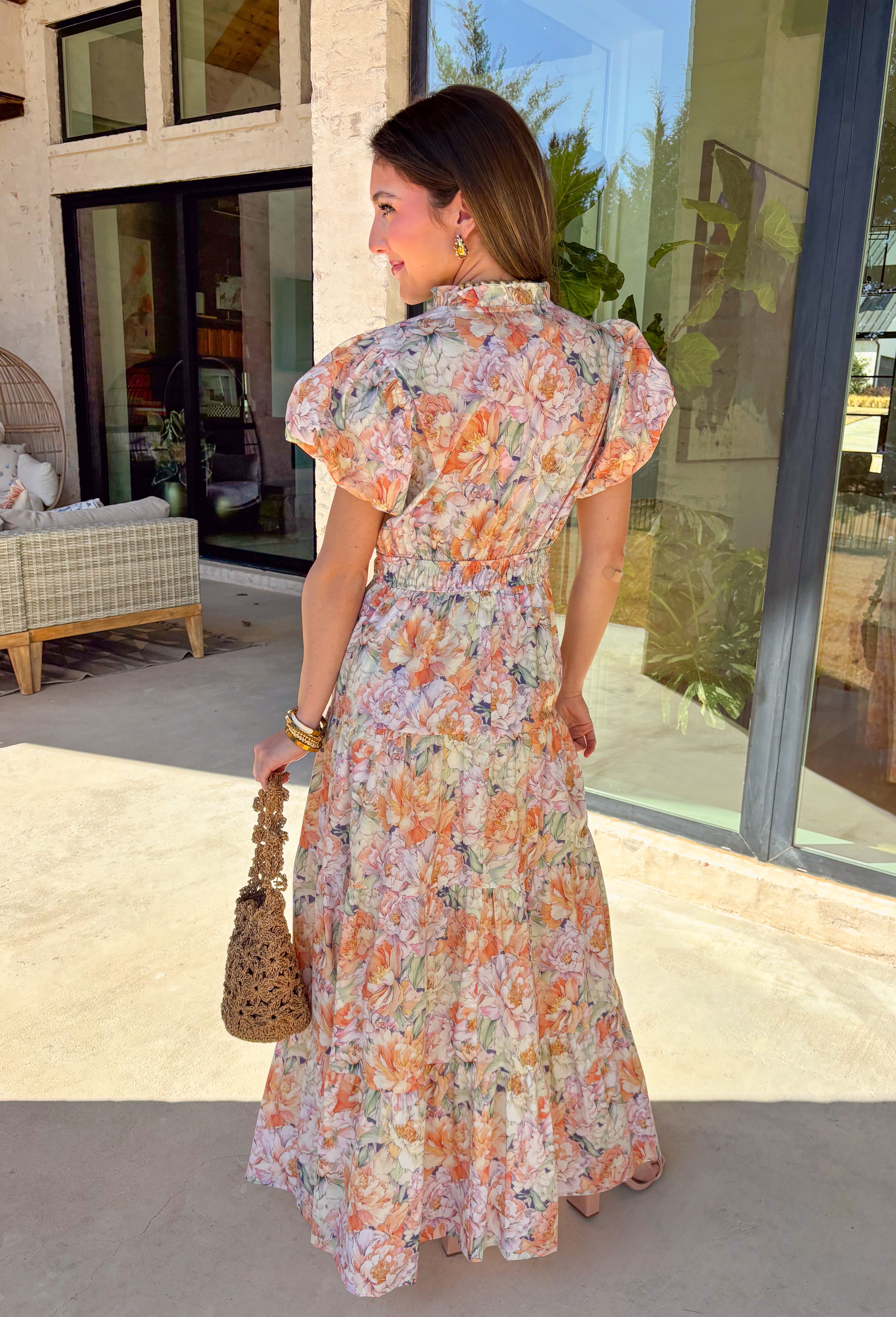 Soft, romantic, and made for spring days, this pastel floral maxi dress by Entro is as easy as it is pretty. Featuring a light, airy floral print in soft spring hues, this dress flows beautifully with its tiered skirt and flattering elastic waist. The subtle ruffle neckline and v-neckline add a delicate touch, while the puff sleeves bring just the right amount of charm. Fully lined and crafted from breathable cotton, it’s perfect for everything from brunch to spring celebrations.
