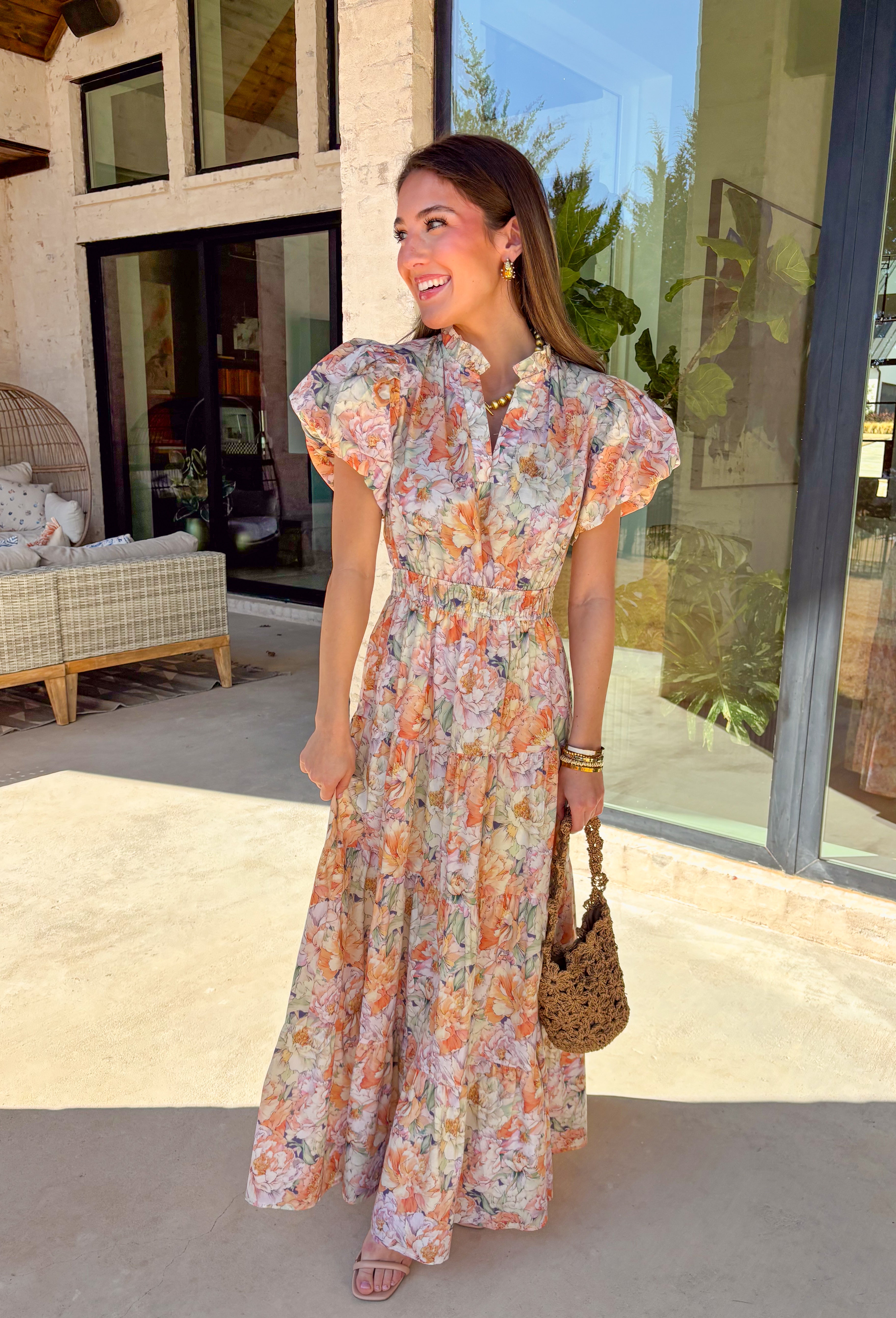 Soft, romantic, and made for spring days, this pastel floral maxi dress by Entro is as easy as it is pretty. Featuring a light, airy floral print in soft spring hues, this dress flows beautifully with its tiered skirt and flattering elastic waist. The subtle ruffle neckline and v-neckline add a delicate touch, while the puff sleeves bring just the right amount of charm. Fully lined and crafted from breathable cotton, it’s perfect for everything from brunch to spring celebrations.