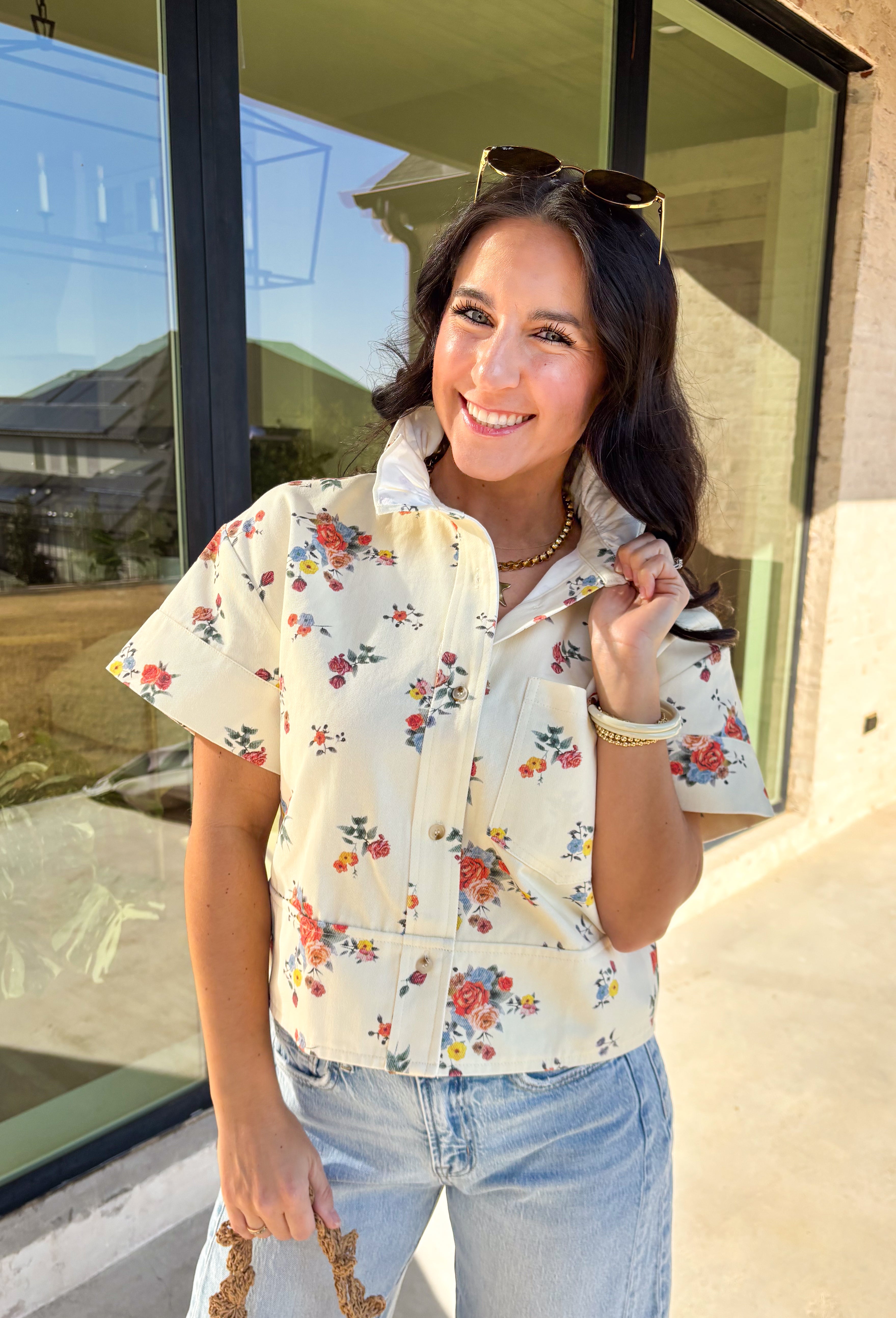 Easy, playful, and perfect for spring, this cream short sleeve button-down top by Entro has that effortless denim-inspired feel with a fun seasonal twist. Designed with a colorful floral print throughout, it brings the prettiest pops of color to a soft, structured cotton base. The ruffle neckline adds a sweet, feminine touch, while the chest pocket keeps the look casual and everyday-ready. This is one of those throw-on tops that instantly makes your outfit feel put together.