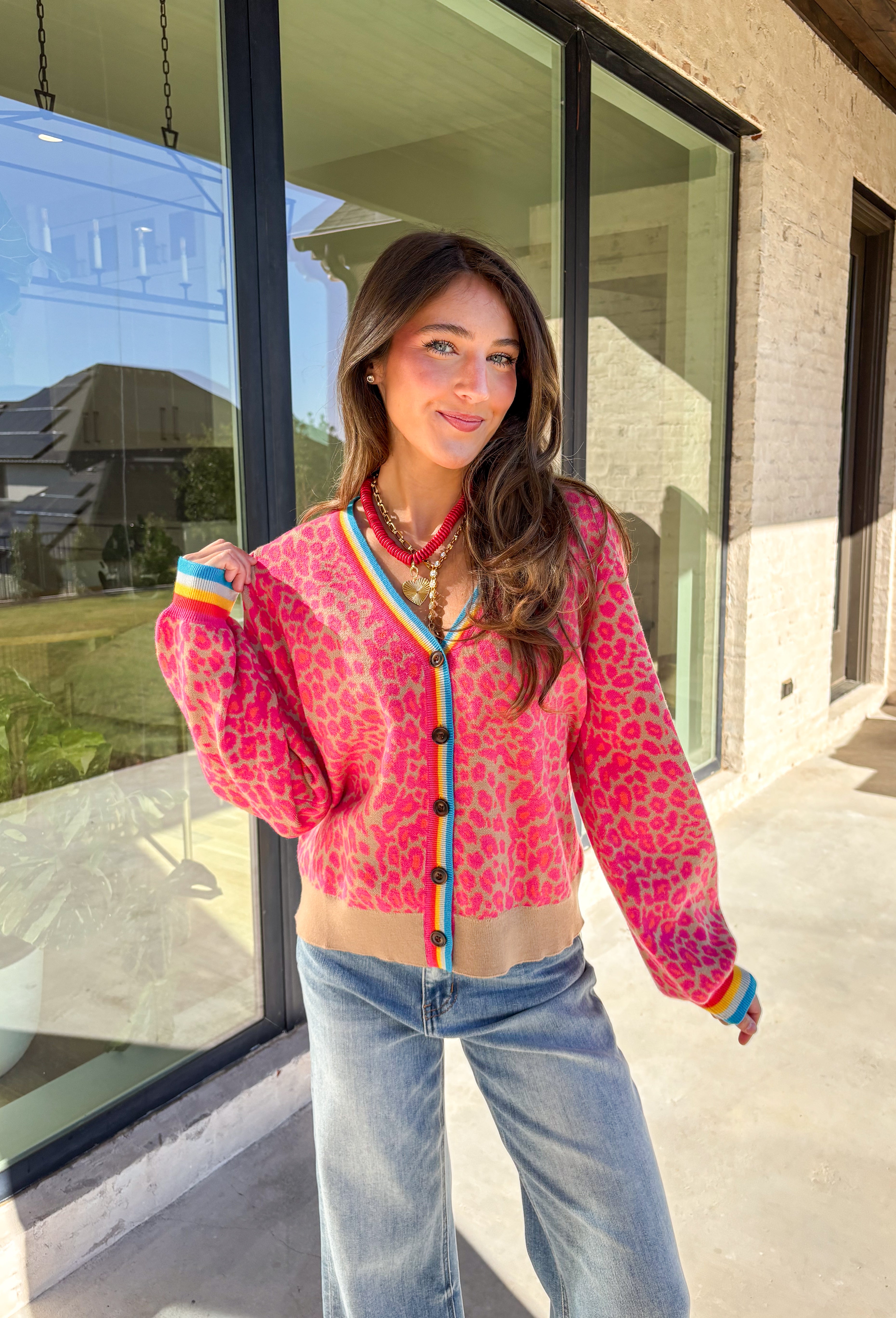 Get ready to turn heads and break up those neutral fall layers with a pop of wild color. This button-down leopard cardigan takes cozy to the next level with its bold pink print on a soft tan background—perfect for making your everyday denim look feel instantly exciting. The colorful trim adds even more personality, making this the ultimate statement layering piece.