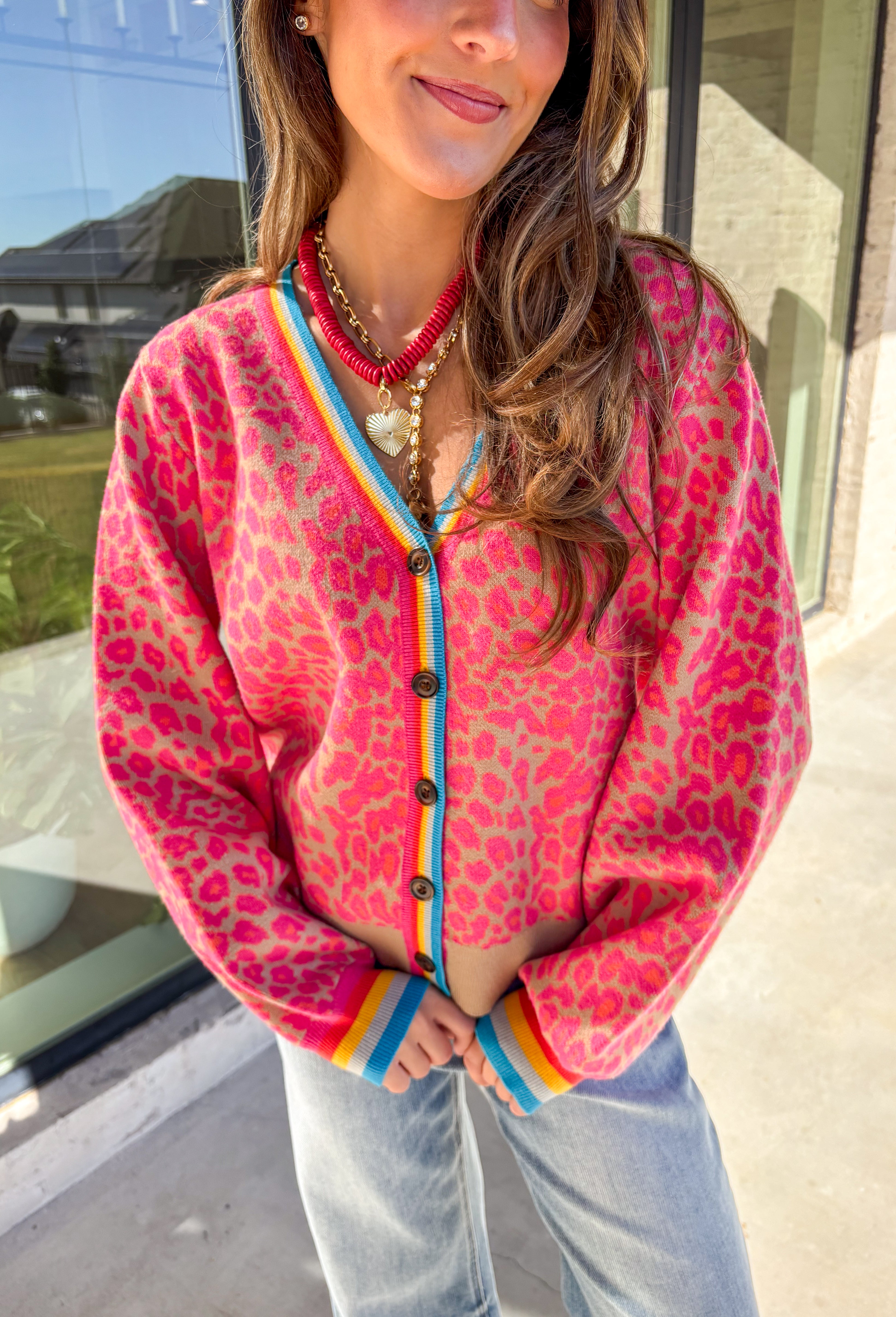 Get ready to turn heads and break up those neutral fall layers with a pop of wild color. This button-down leopard cardigan takes cozy to the next level with its bold pink print on a soft tan background—perfect for making your everyday denim look feel instantly exciting. The colorful trim adds even more personality, making this the ultimate statement layering piece.