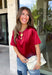 A rich red satin gives this short sleeve top from Sunday Edition the perfect festive feel for the holiday season. The smooth fabric adds a pretty touch of shine, while the lace hem brings in a soft detail that dresses up the simple silhouette. A keyhole opening at the back adds a finishing touch without taking away from the easy-to-style design. It’s a fun option for everything from Christmas parties and holiday dinners to festive date nights and seasonal get-togethers. 
