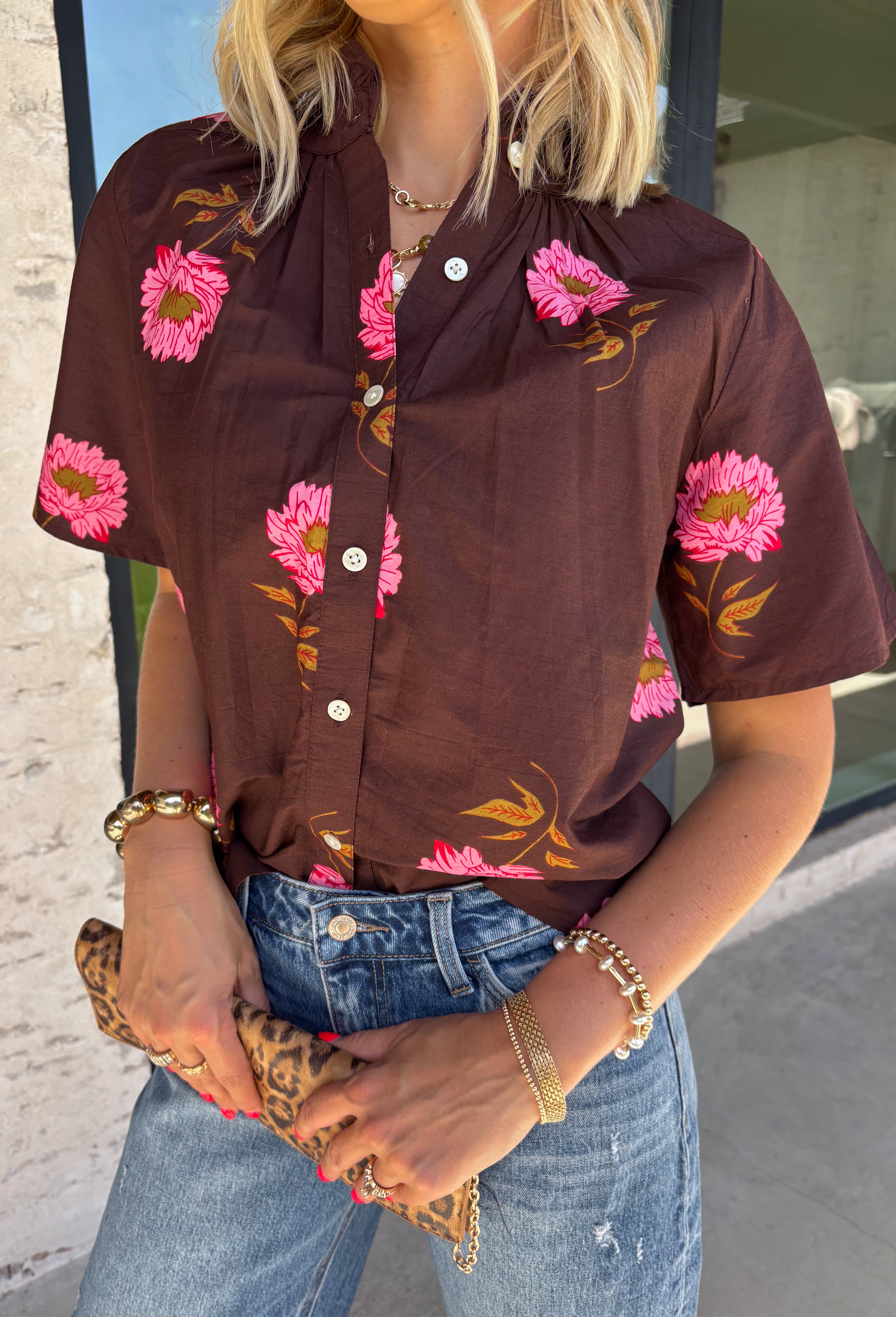 Bring a touch of effortless charm to your everyday wardrobe with this beautiful floral blouse from THML. Designed with a rich brown backdrop and a pink floral print, this timeless top is full of feminine details you'll love. The button-front design offers classic style, while the subtle ruffle neckline adds a delicate finishing touch. Crafted from breathable cotton, this versatile blouse transitions beautifully from the office to weekend outings, making it an easy favorite for the fall season.
