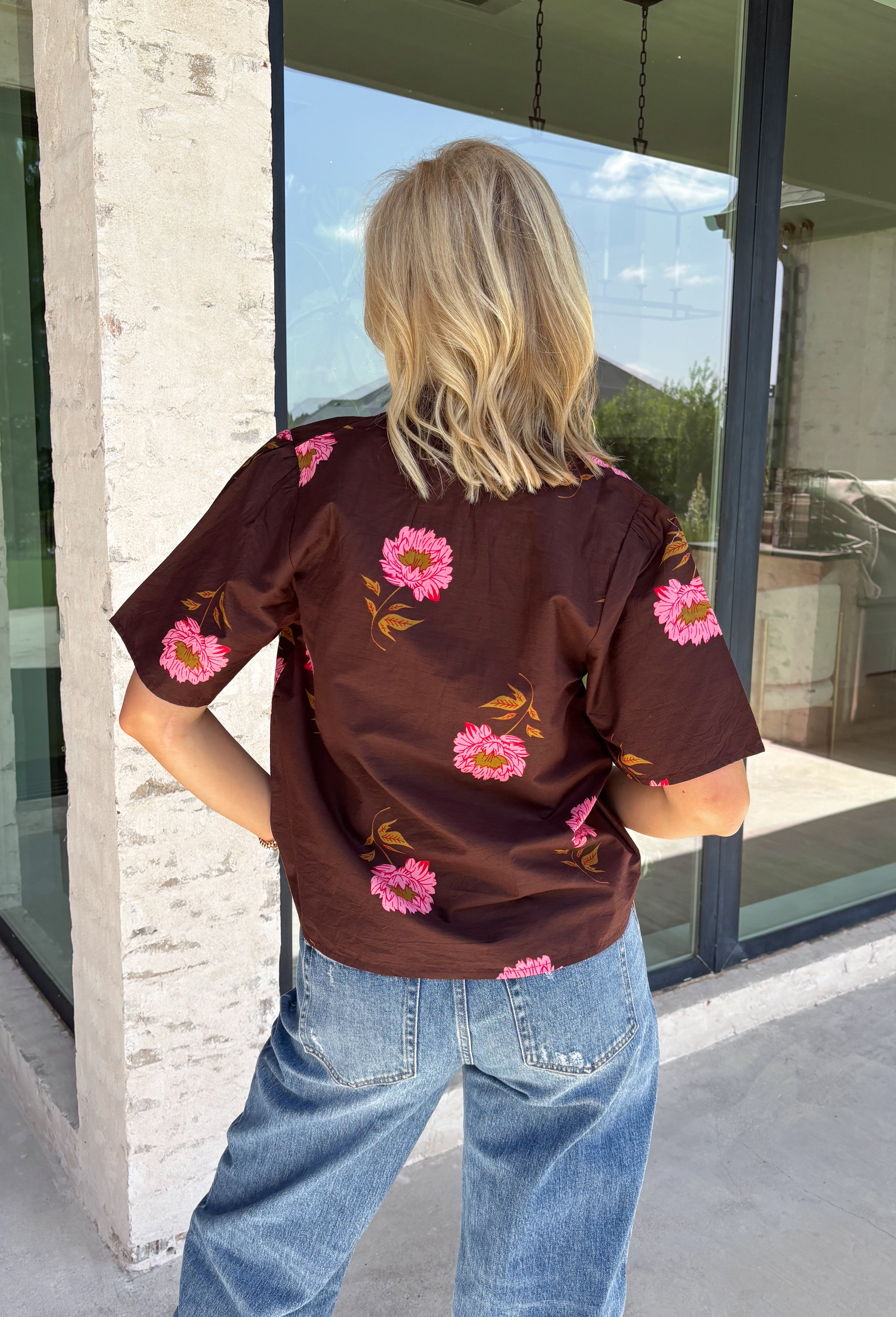 Bring a touch of effortless charm to your everyday wardrobe with this beautiful floral blouse from THML. Designed with a rich brown backdrop and a pink floral print, this timeless top is full of feminine details you'll love. The button-front design offers classic style, while the subtle ruffle neckline adds a delicate finishing touch. Crafted from breathable cotton, this versatile blouse transitions beautifully from the office to weekend outings, making it an easy favorite for the fall season.