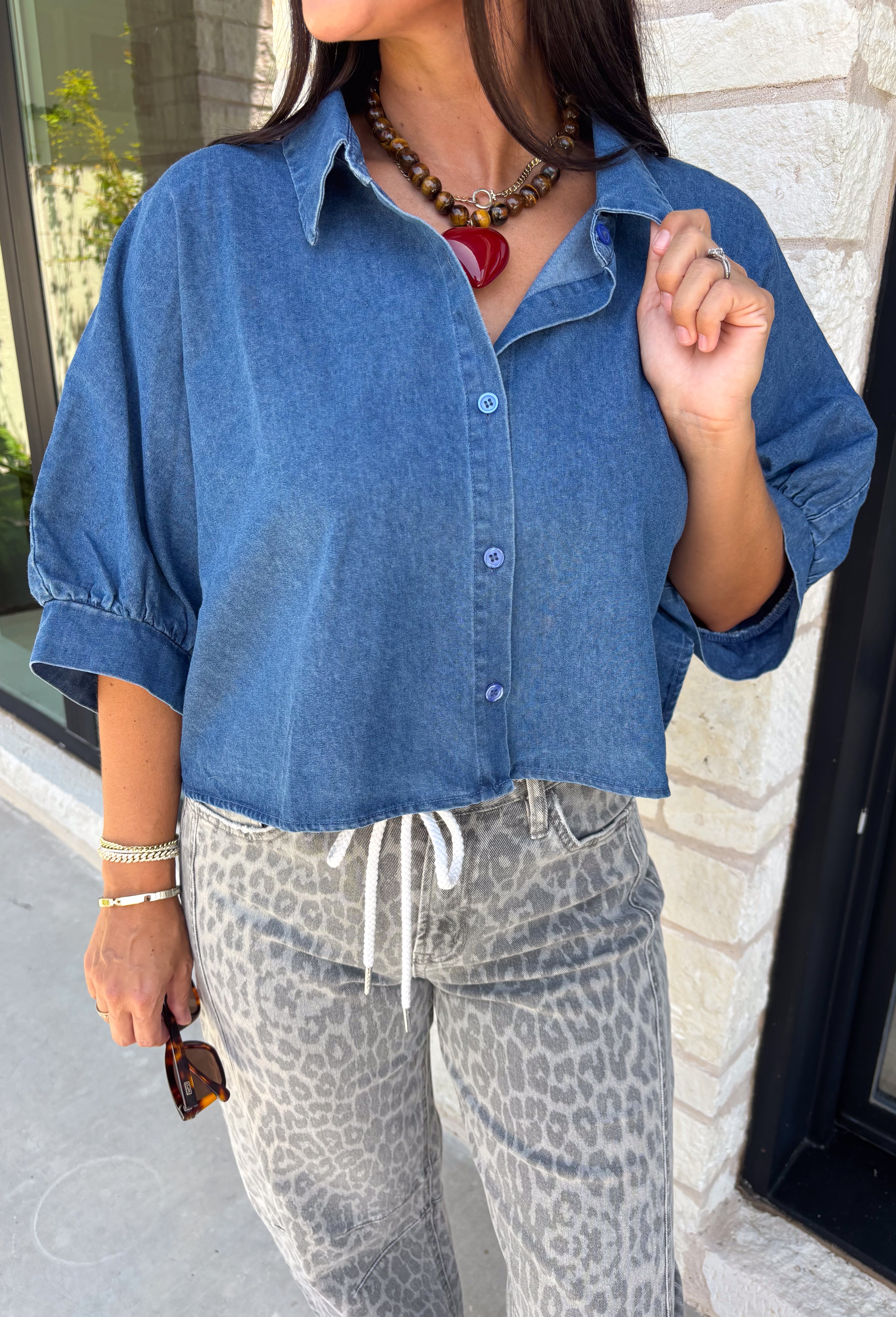 A classic denim top is a staple you'll reach for season after season! Crafted from soft medium wash denim, this effortless button-down blouse is designed with relaxed dolman sleeves and a subtle high-low hem for an easy, flattering fit. The collared neckline adds a timeless touch, making it simple to dress up or keep casual. Whether you're layering it under a blazer or wearing it on its own with your favorite fall denim, this versatile piece belongs in every autumn wardrobe.